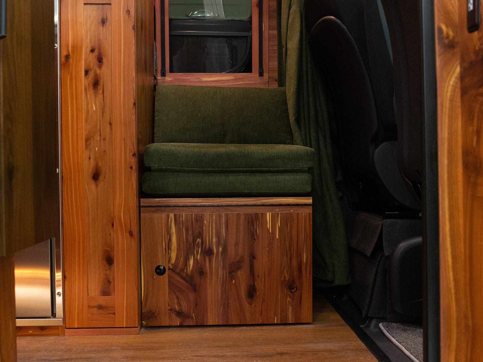 Ein Fenster unter einem grünen Sitz, umgeben von Holz.
