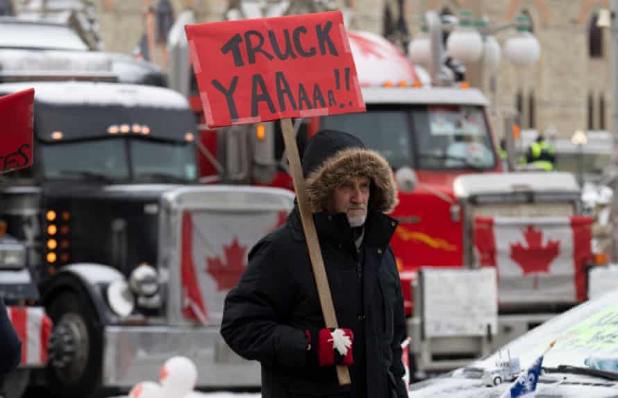 Ein Demonstrant geht am Donnerstag in Ottawa um geparkte Fahrzeuge vor dem Parliament Hill herum.