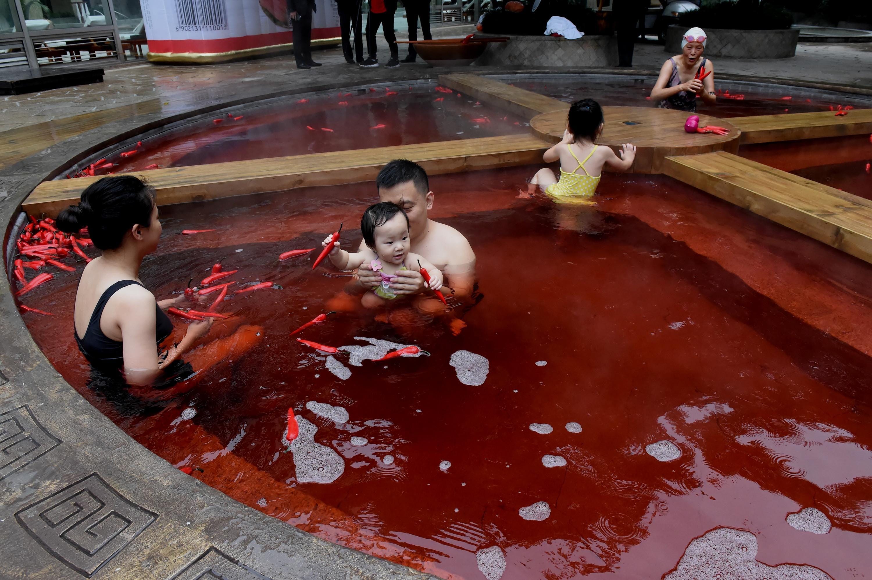 Die Bürger baden im Chongqing Ronghui Hot Spring Resort in einer roten heißen Quelle in Form eines riesigen heißen Topfes aus Kräutern der traditionellen chinesischen Medizin und Rotwein.
