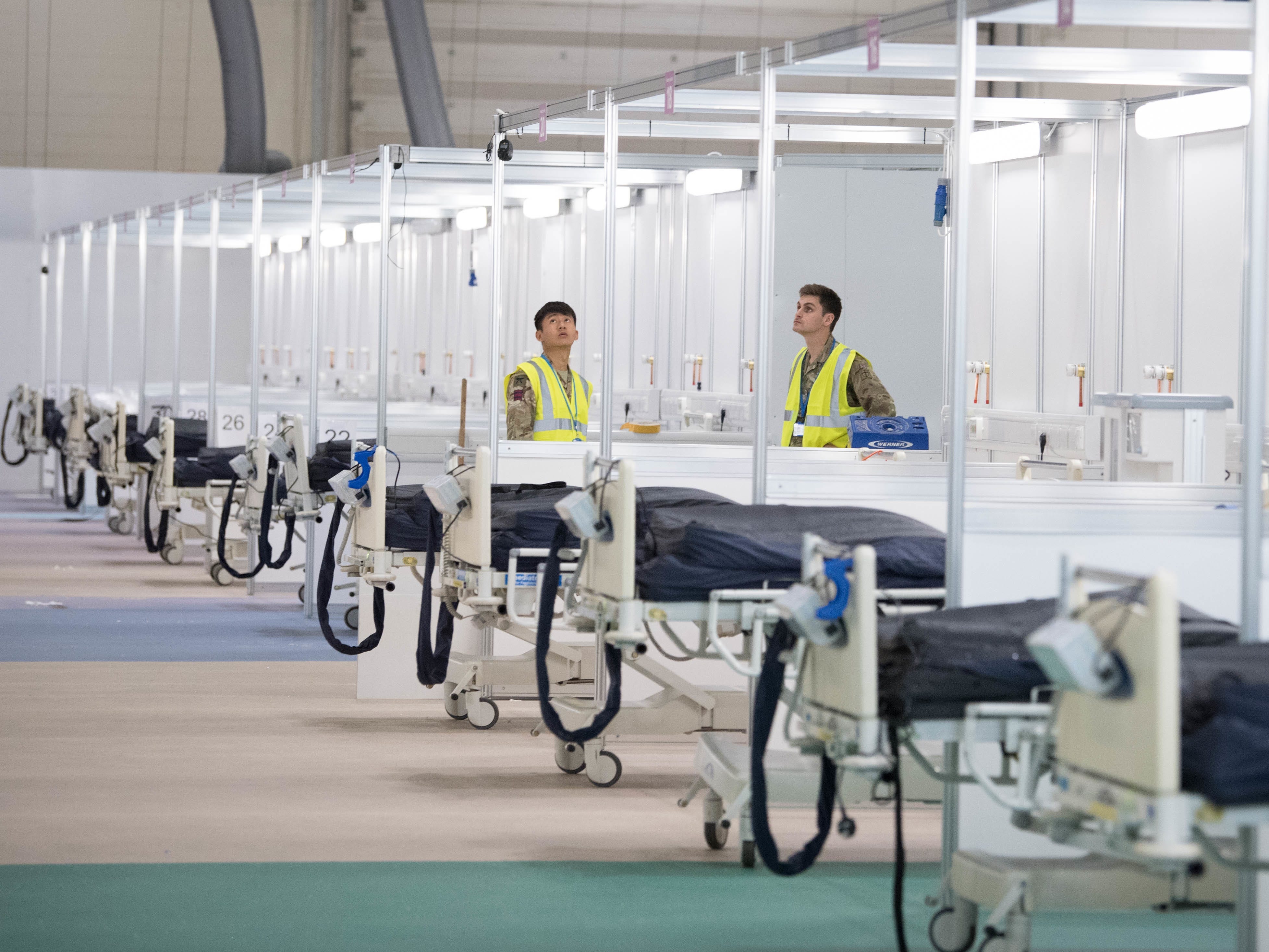 Soldaten und private Auftragnehmer helfen bei der Vorbereitung des ExCel-Zentrums, das in das provisorische NHS-Nightingale-Krankenhaus umgewandelt wird.