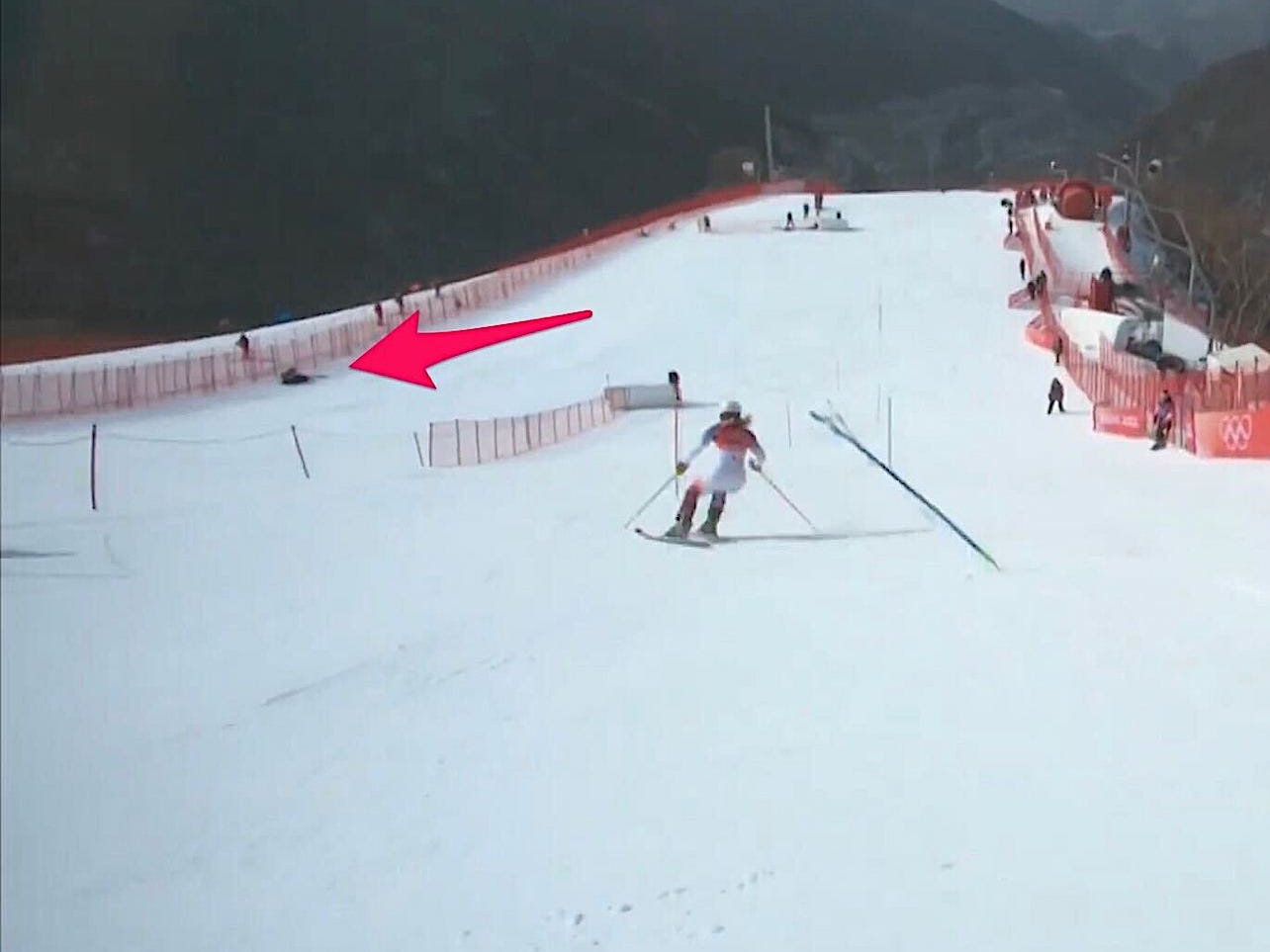 Der Screenshot zeigt einen Pfeil, der auf Mikaela Shiffrin zeigt, die nach einem Sturz an der Seite der Slalomstrecke sitzt.