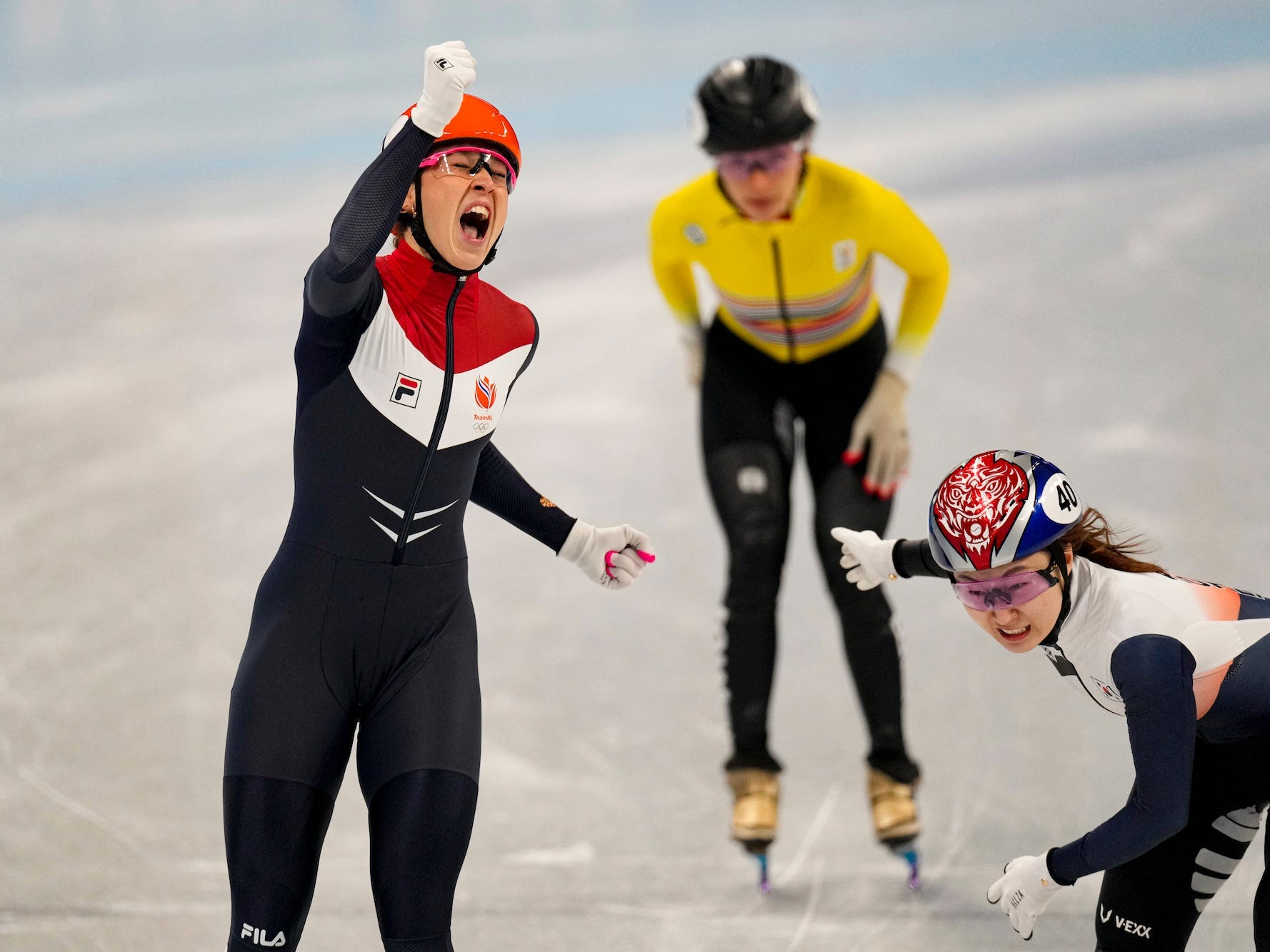 Suzanne Schulting vom Team Niederlande feiert, während sie vor zwei anderen Skatern ins Ziel kommt.