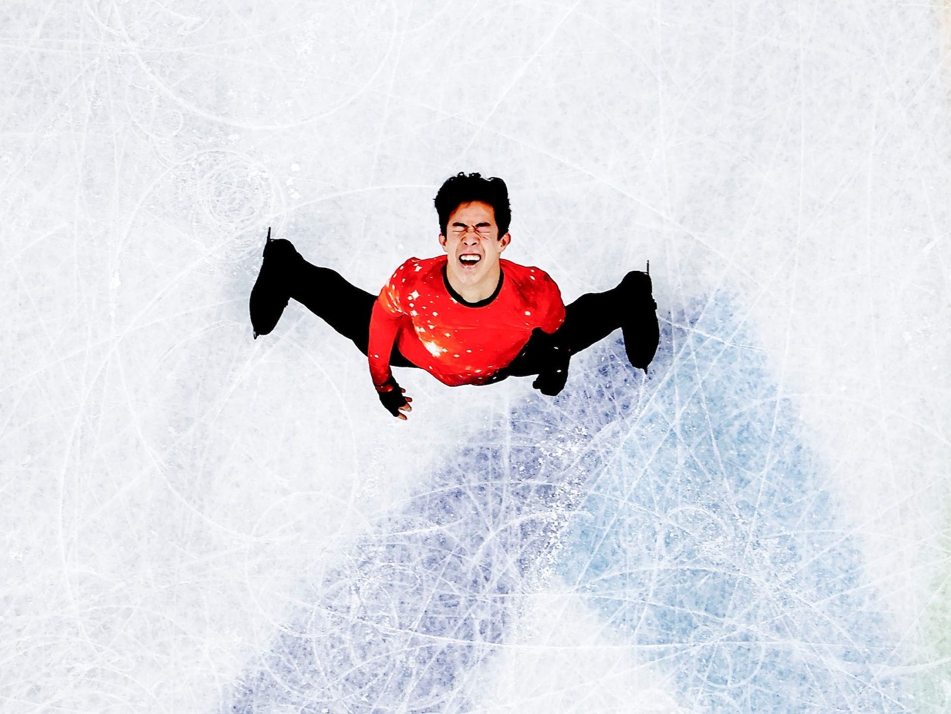 Eine Aufnahme von oben zeigt Nathan Chen lächelnd beim Eiskunstlauf bei den Olympischen Spielen in Peking.