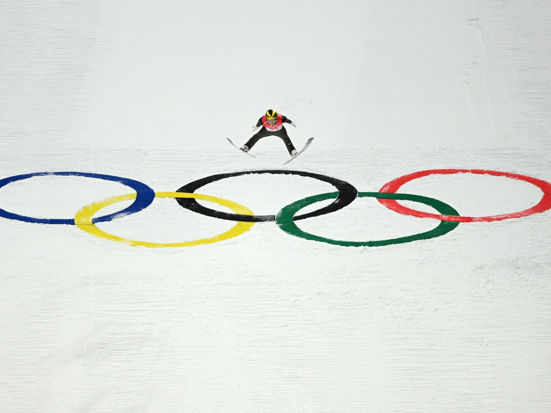 Ein Skispringer landet bei den Olympischen Spielen in Peking auf den Olympischen Ringen.