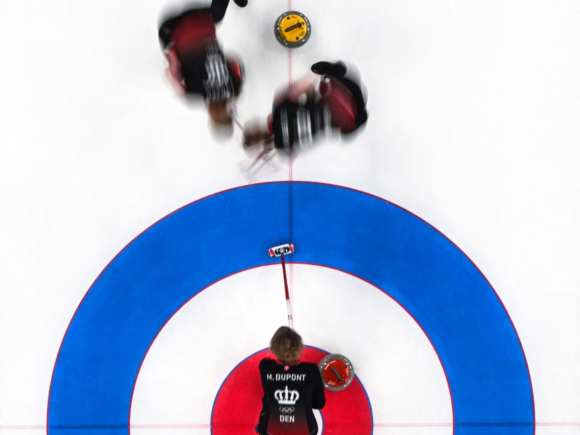 Eine Aufnahme von oben zeigt Dänemarks Curling-Team, das einen Schuss ausführt.