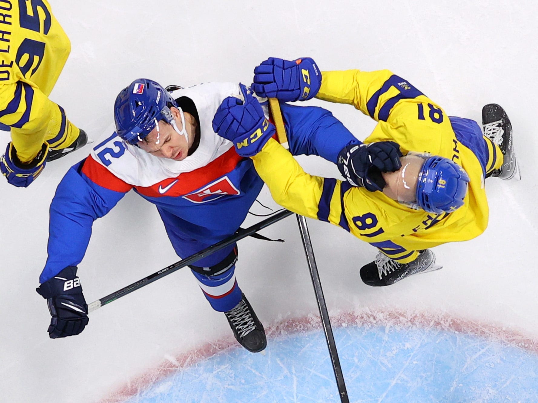 Ein slowakischer Eishockeyspieler schlägt einen schwedischen Eishockeyspieler bei den Olympischen Spielen in Peking.