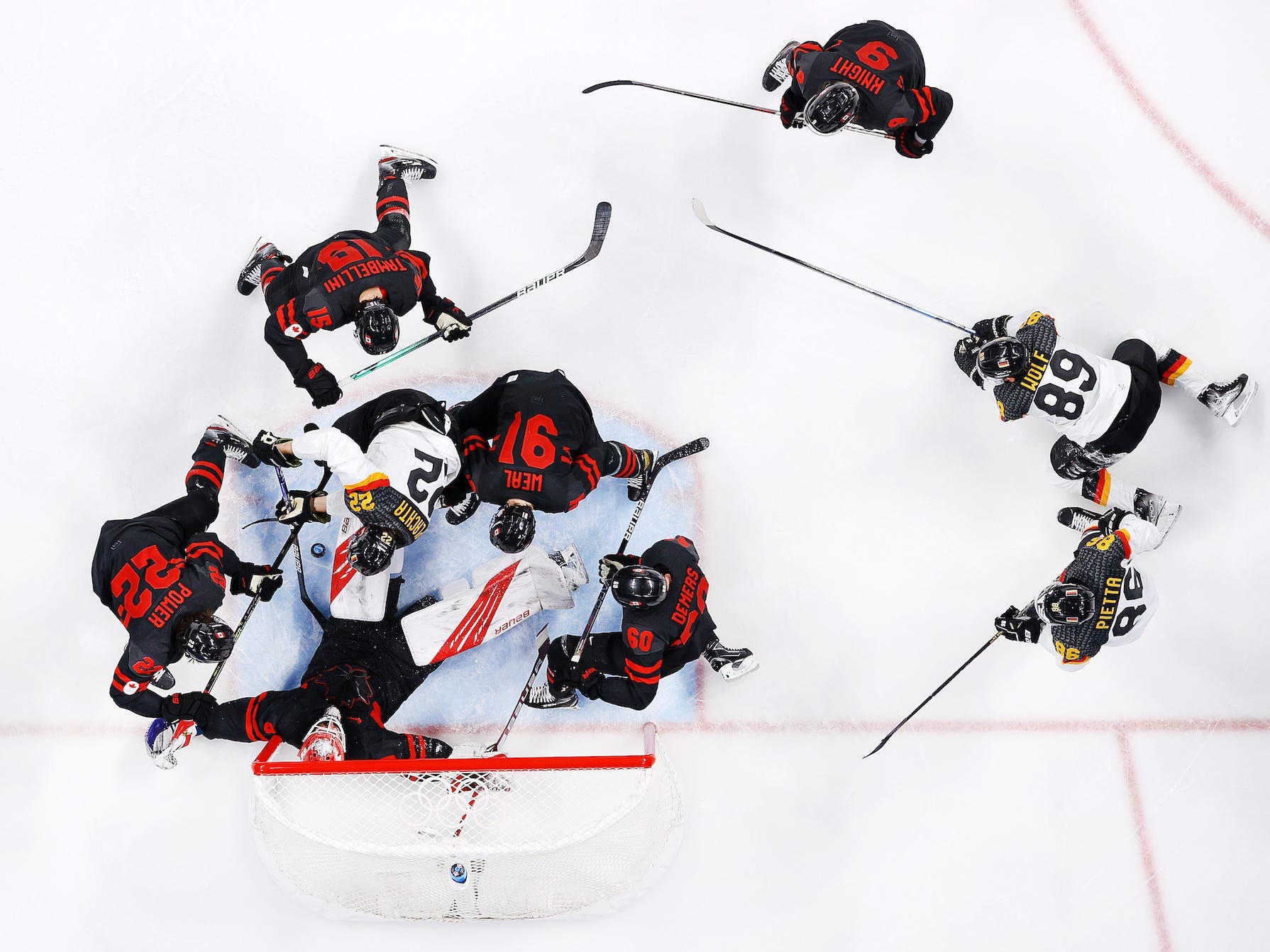 Die Aufnahme von oben zeigt eine Ansammlung von Eishockeyspielern vor dem Netz bei den Olympischen Spielen in Peking.