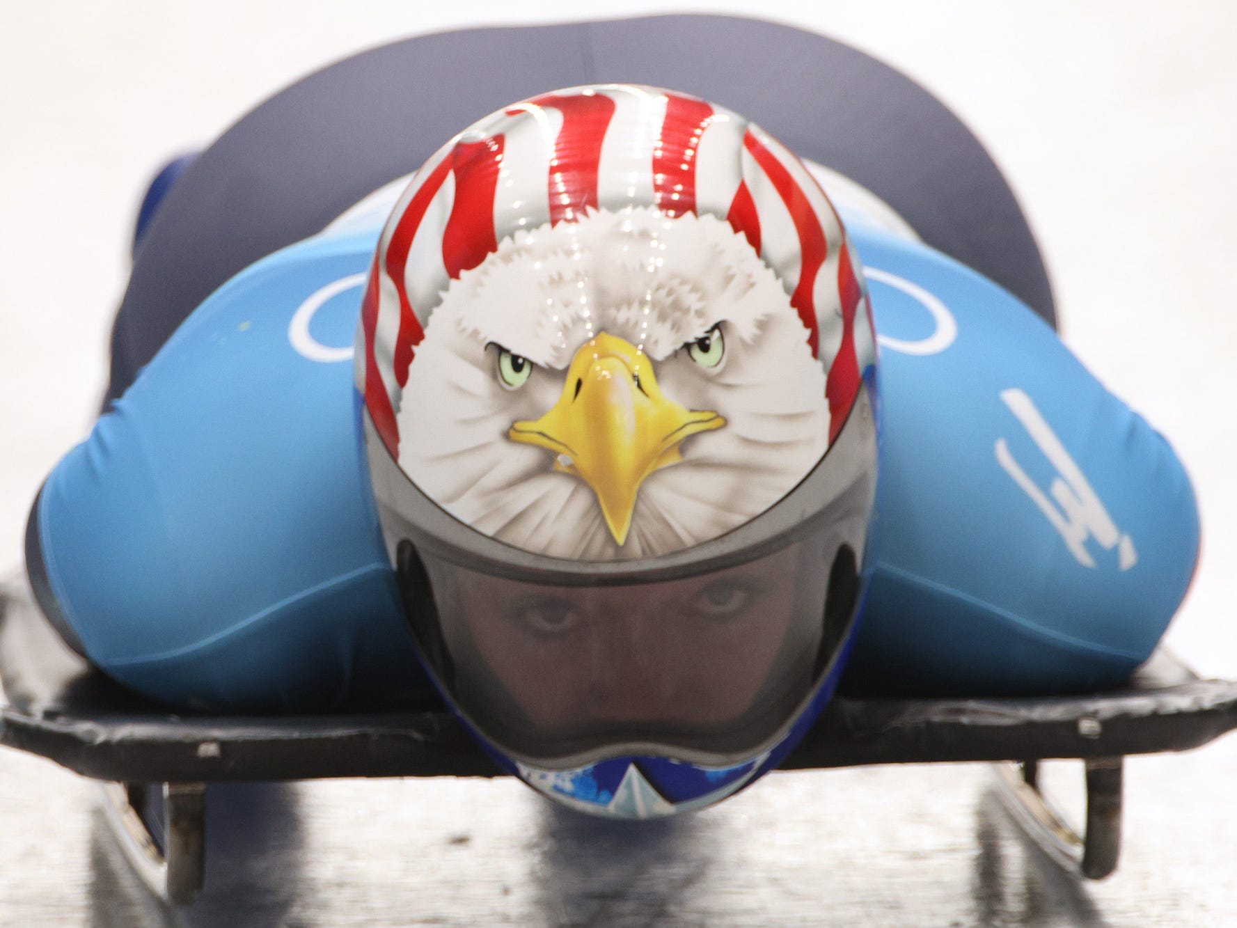 Ein Skeleton-Rennfahrer bei den Olympischen Spielen trägt einen Helm mit Adler.