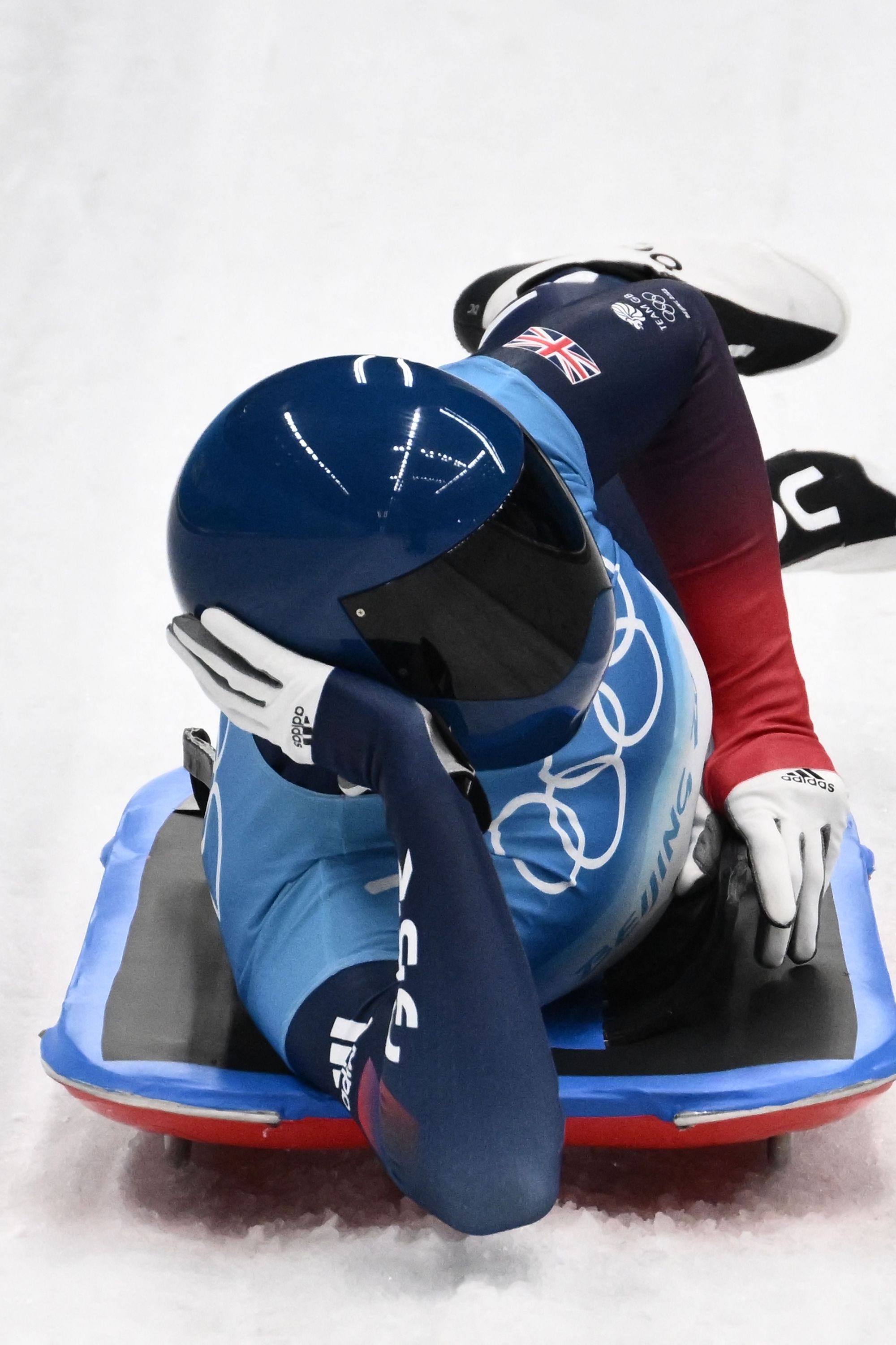 Ein Skeleton-Rennfahrer liegt bei den Olympischen Spielen in Peking in Pose auf der Seite.