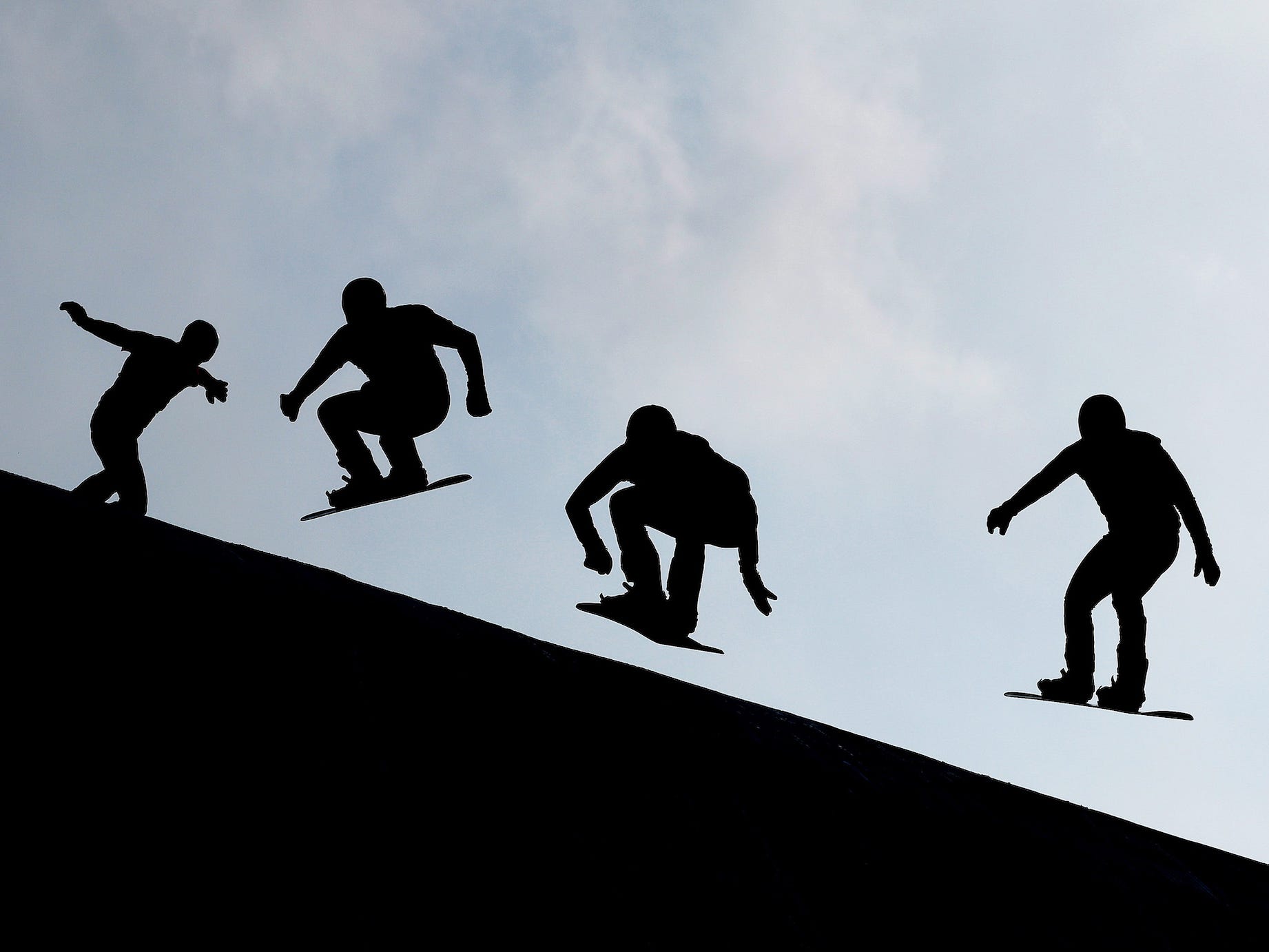 Silhouetten von vier Snowboardern, die bei den Olympischen Spielen in Peking im Snowboardcross antreten.