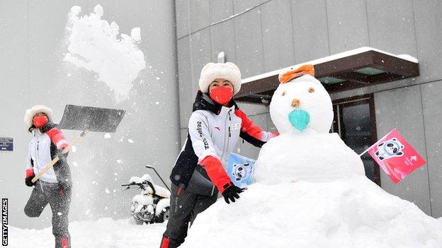 Freiwillige der Olympischen Spiele spielen mit einem Schneemann in Peking