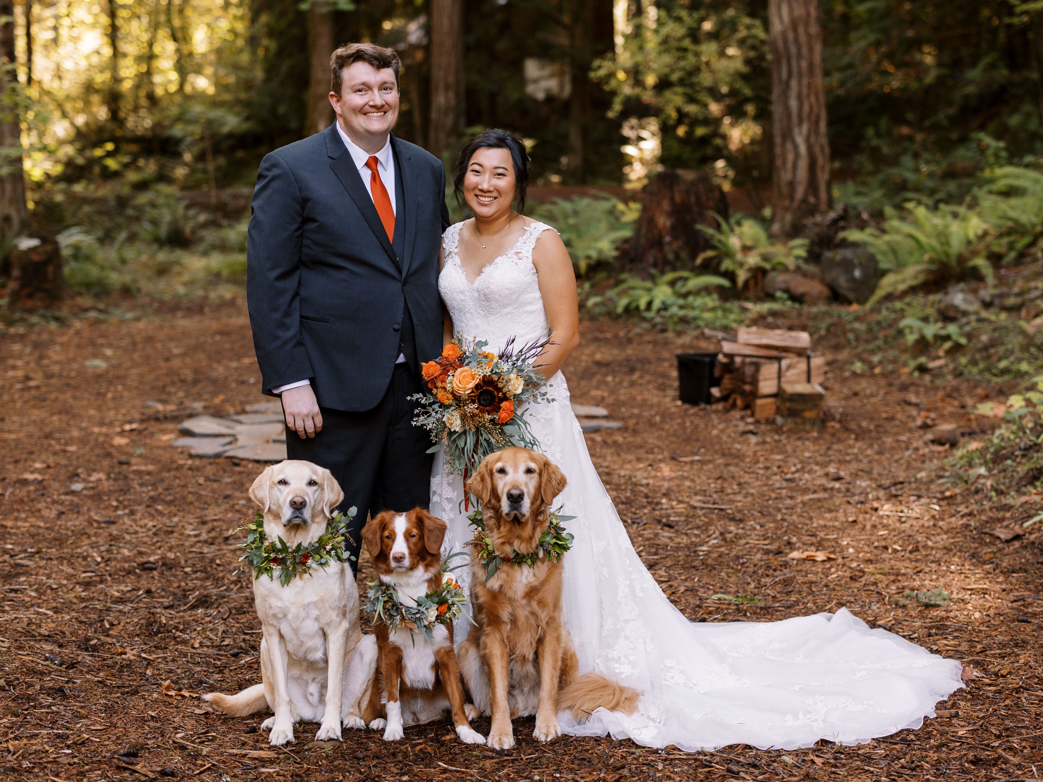 Portrait der Braut und des Bräutigams und ihrer drei Hunde, die Kranzhalsketten tragen.