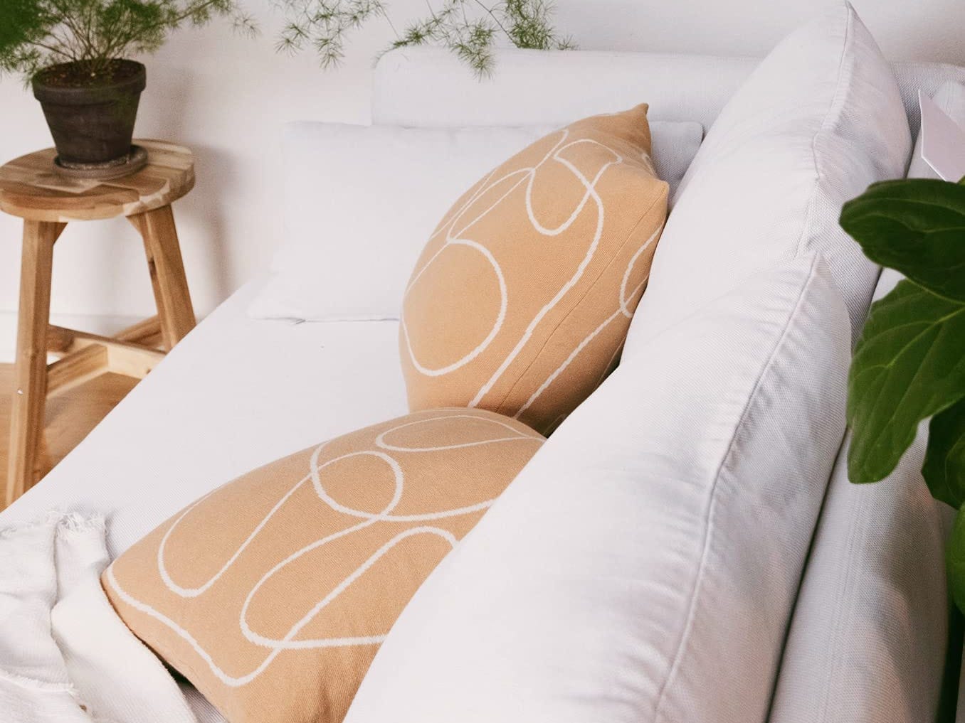 Zwei terrakottafarbene Wurfkissen mit weißen abstrakten Linien auf einer weißen Couch