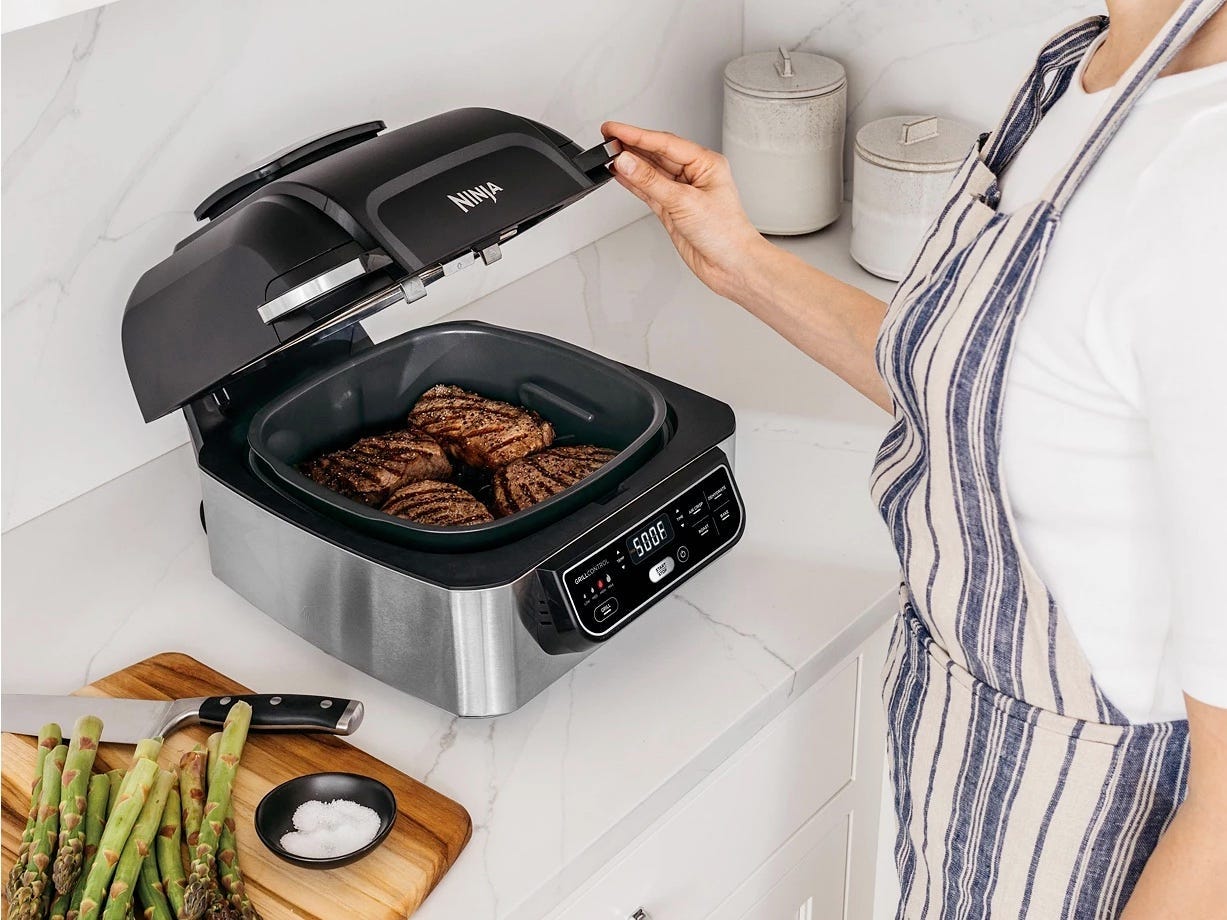 Bild einer Frau, die eine Ninja-Heißluftfritteuse verwendet, um Fleisch zu kochen, Macy's Appliance Deals 2022