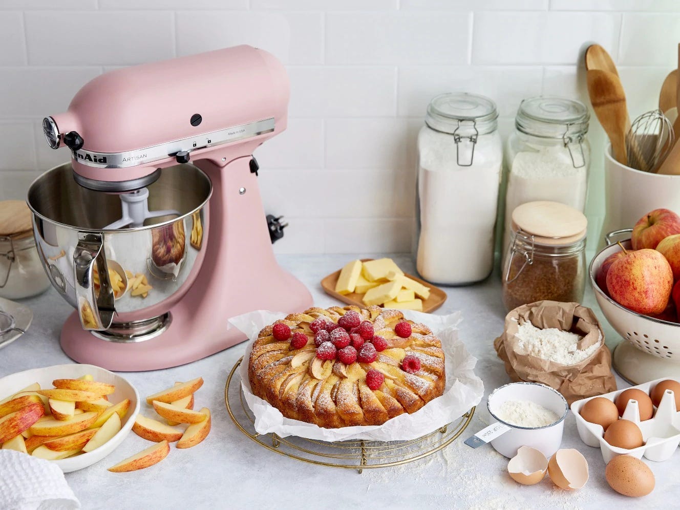 Bild eines pinkfarbenen KitchenAid-Mixers neben einer Pfirsichtarte und Backzubehör, KitchenAid Appliance Deals 2022