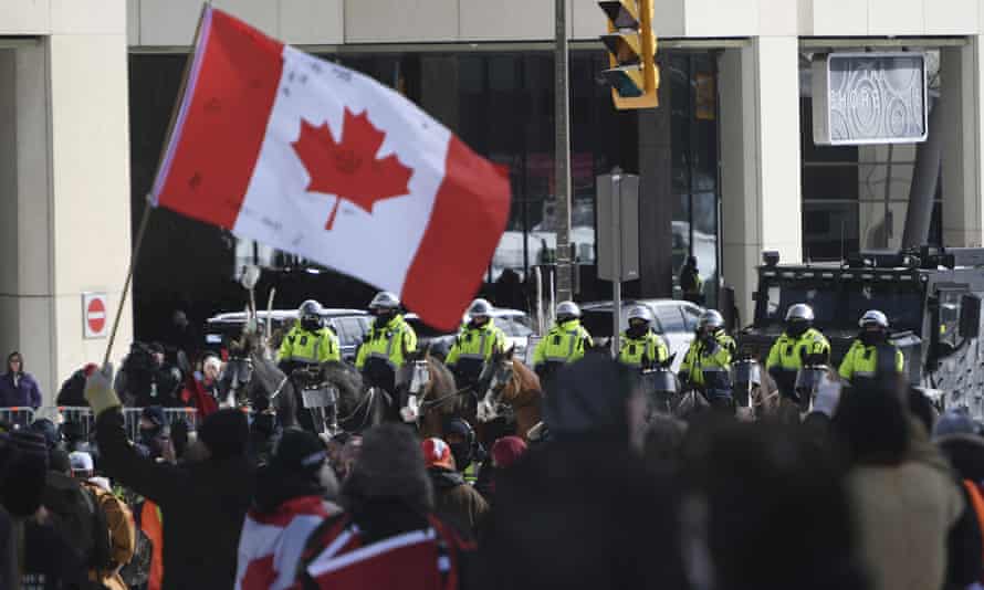 Polizisten zu Pferd und ein gepanzertes Polizeifahrzeug werden bei Protesten in Ottawa am Freitag vor Demonstranten positioniert.
