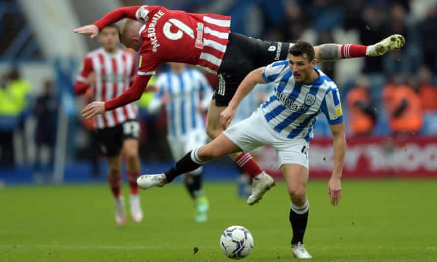 Matty Pearson von Huddersfield mit dem Spitznamen „Keighley Cannavaro“ bleibt am Boden, während Oliver McBurnie von Sheffield United in die Luft fliegt.