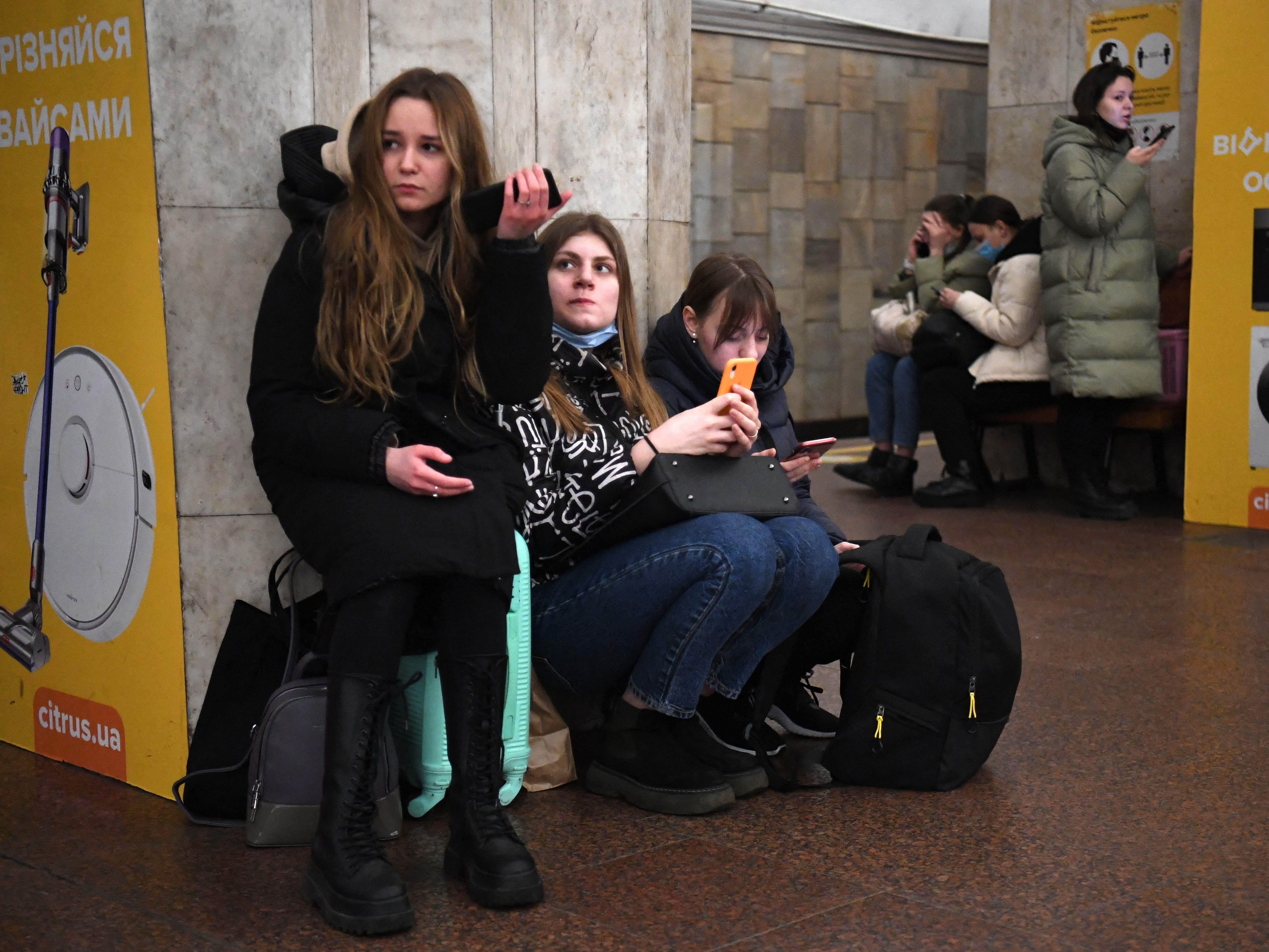 Mädchen halten ihr Mobiltelefon, als sie am Donnerstagmorgen Ortszeit inmitten eines russischen Angriffs auf ihr Land in einer U-Bahn-Station in Kiew, Ukraine, Zuflucht suchen.