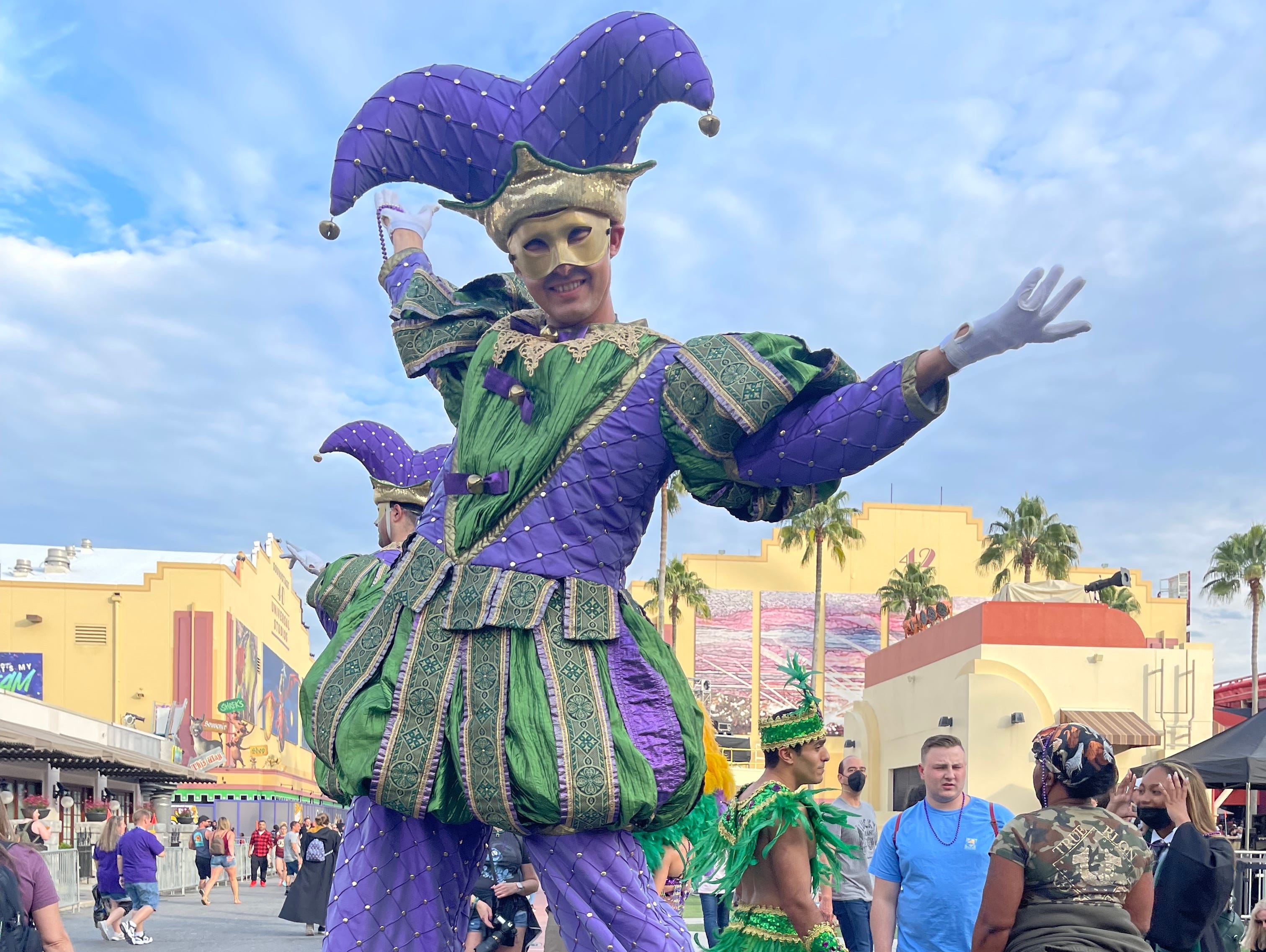 Mann auf Stelzen in lila und grüner Clownskleidung bei Universal Orlando Mardi Gras