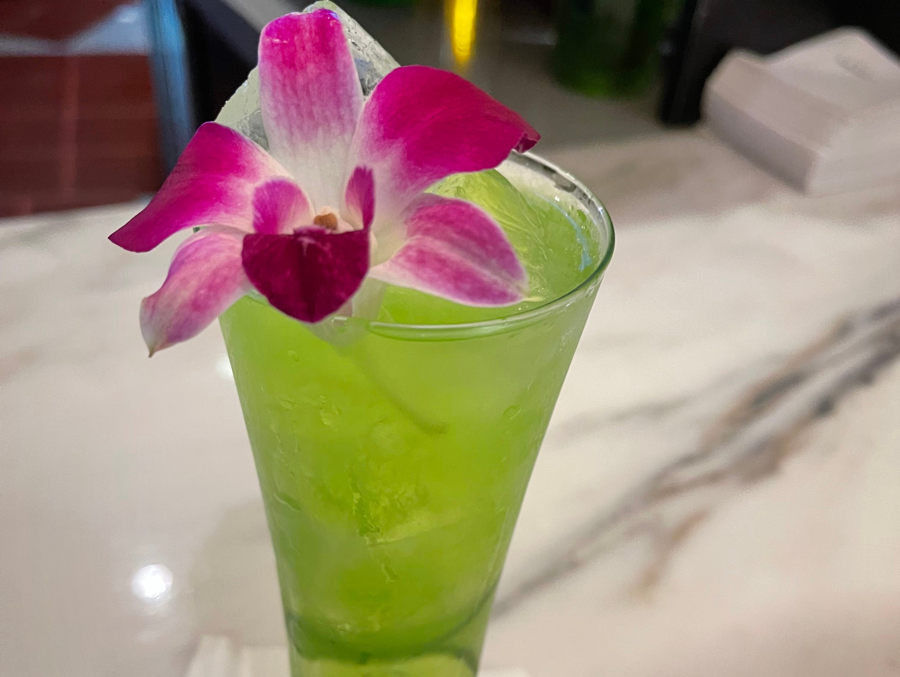 Grüner Cocktail mit rosafarbener Blumengarnitur in einem Universal Orlando Resort