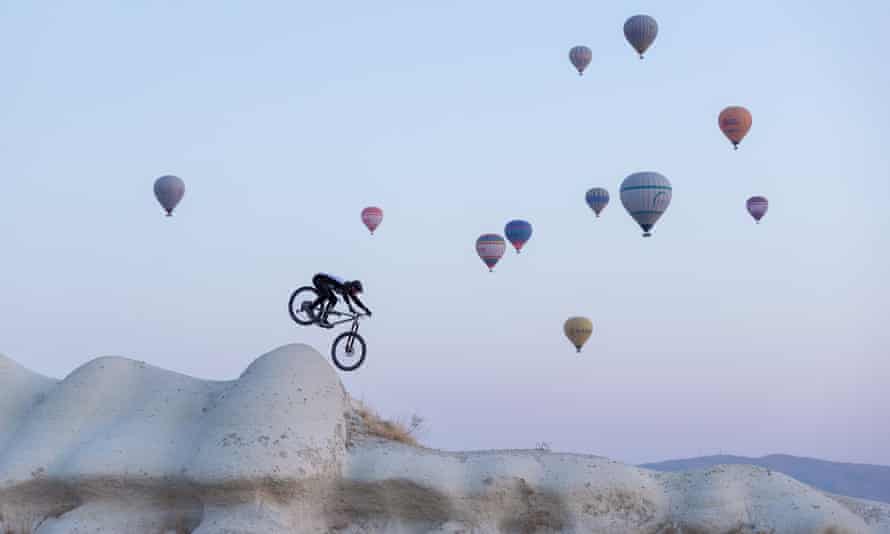 Killion Bron reitet unter einer Wolke aus Heißluftballons durch die Feenkamine von Kappadokien