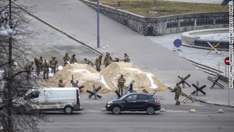 Soldaten sind um Sandhaufen herum zu sehen, mit denen eine Straße in der ukrainischen Hauptstadt Kiew blockiert wurde.