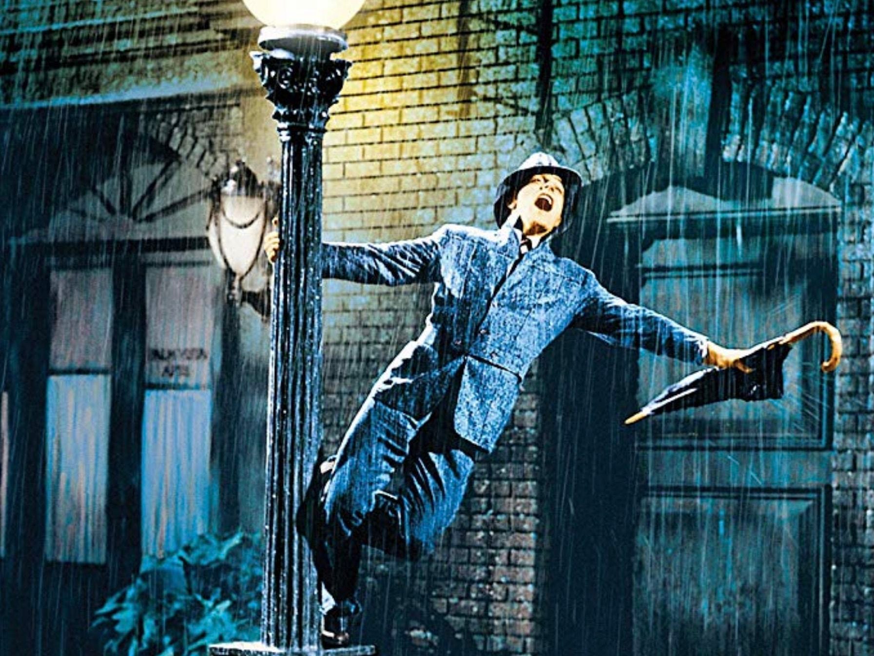 Gene Kelly hängt in Singing In The Rain an einem Laternenpfahl im Regen