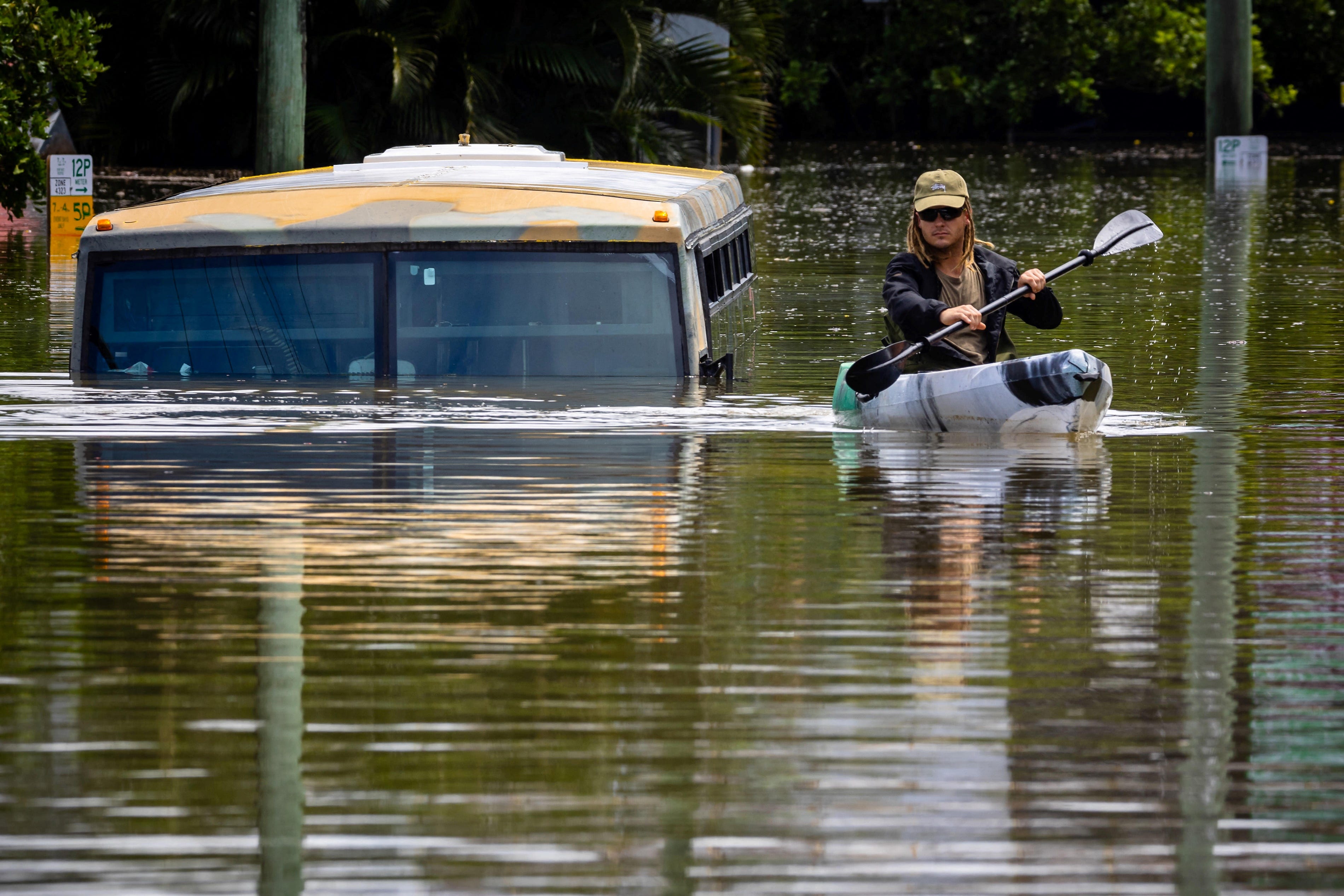 Ein Mann paddelt mit seinem Kajak auf einer überfluteten Straße in der Stadt Milton in einem Vorort von Brisbane