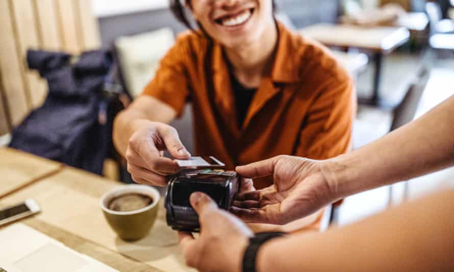 Junger asiatischer Mann, der in einem Café mit Kreditkarte bezahlt