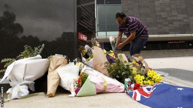 Ein Mann legt Blumen an der Statue von Shane Warne auf dem Melbourne Cricket Ground nieder