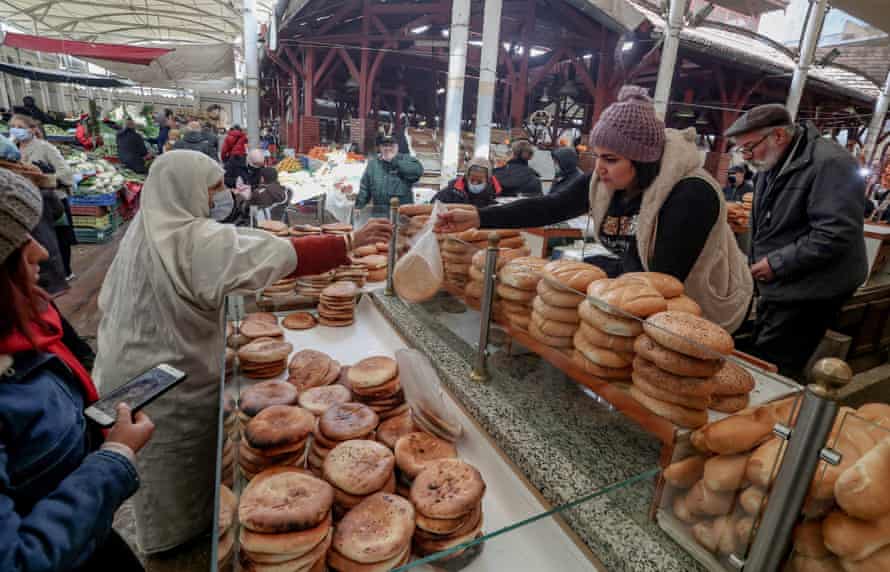 Eine verschleierte Frau kauft Brot an einem Marktstand