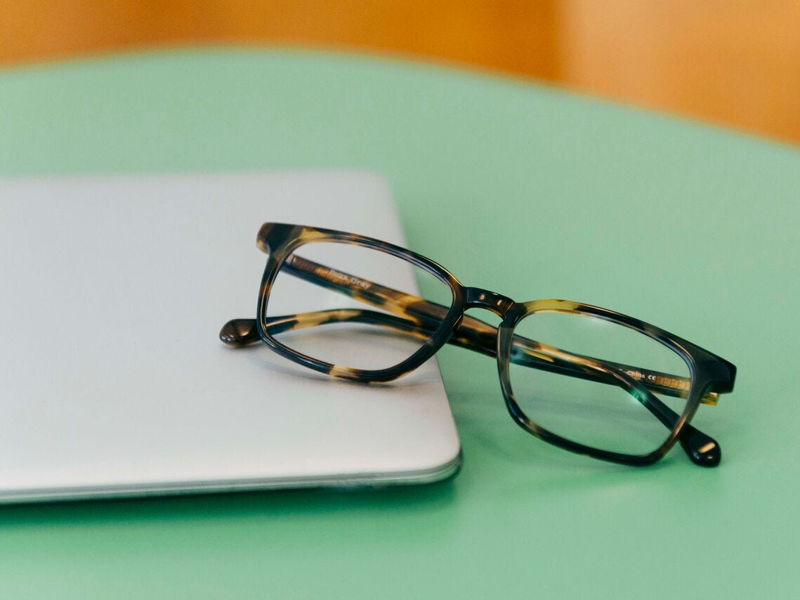 Eine Brille mit braunem Schildpattrahmen, die auf der Kante des Laptops sitzt