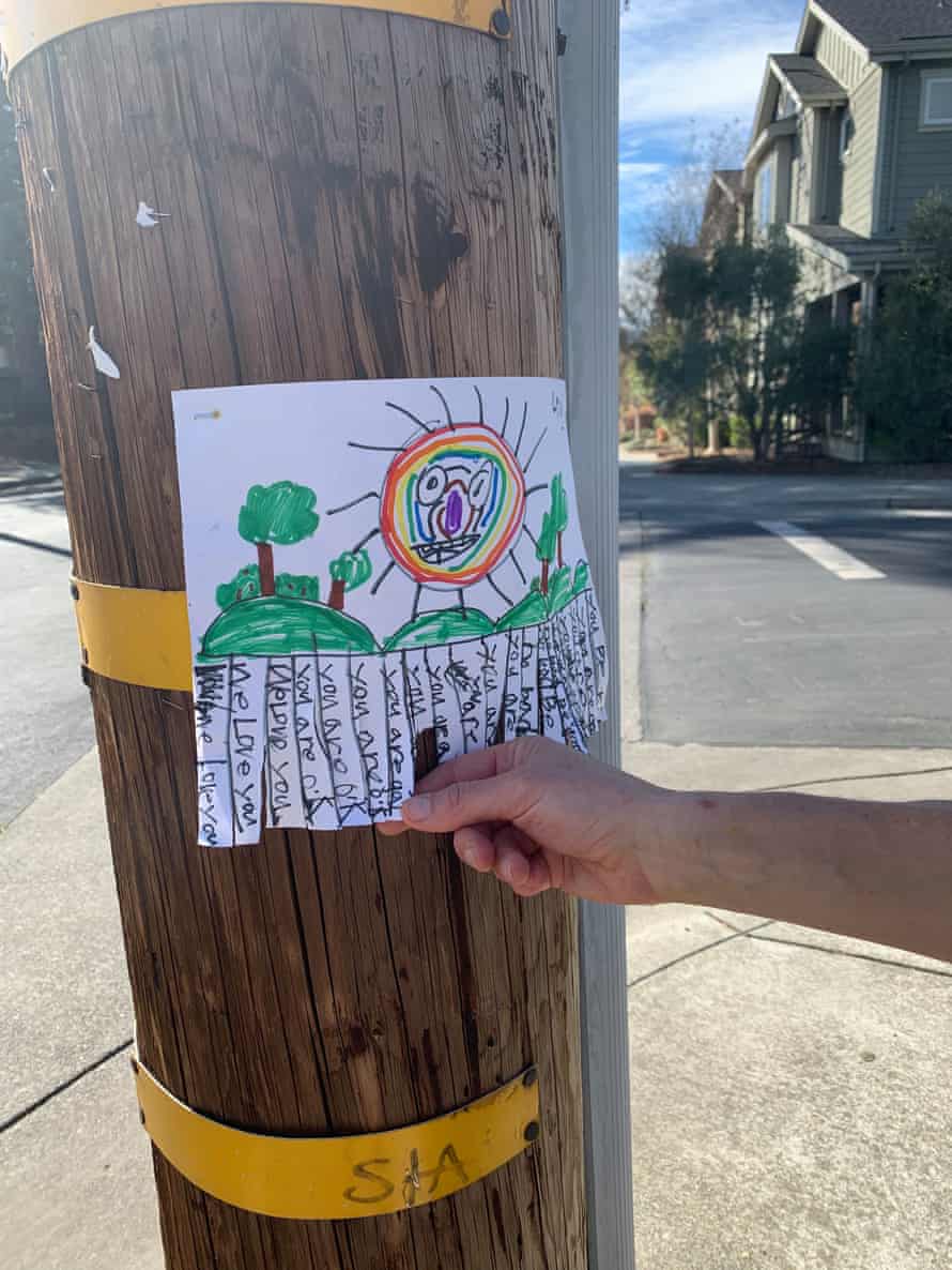 Ein Plakat an einem Telefonmast zeigt eine Zeichnung einer Regenbogensonne mit positiven Botschaften, die abgerissen werden kann.