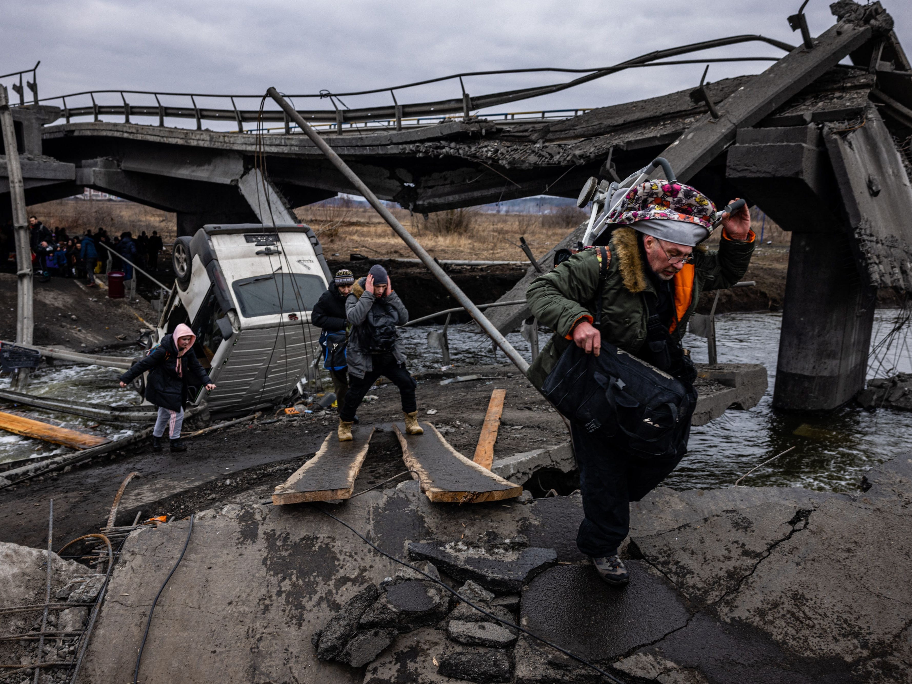 Evakuierte überqueren am 7. März 2022 eine zerstörte Brücke, als sie aus der nordwestlich von Kiew gelegenen Stadt Irpin fliehen.