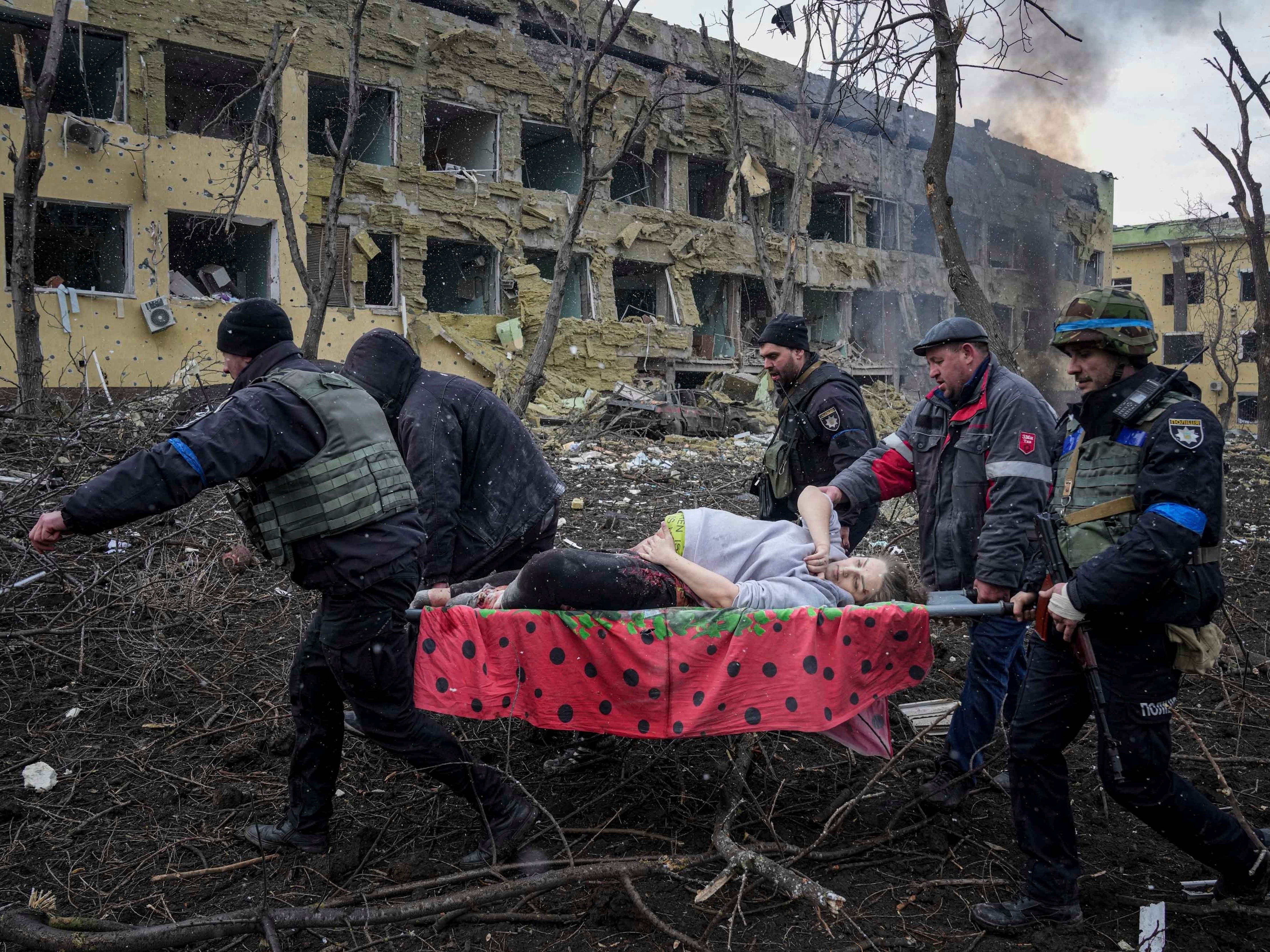 Ukrainische Rettungskräfte und Freiwillige tragen eine verletzte schwangere Frau aus einem Entbindungsheim, das am 9. März 2022 in Mariupol, Ukraine, durch Beschuss beschädigt wurde.
