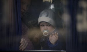 Eine Flüchtlingsfrau hält ein Baby, während sie in einem Bus darauf wartet, dass die ukrainische Polizei Papiere und Habseligkeiten in Browary, Ukraine, kontrolliert