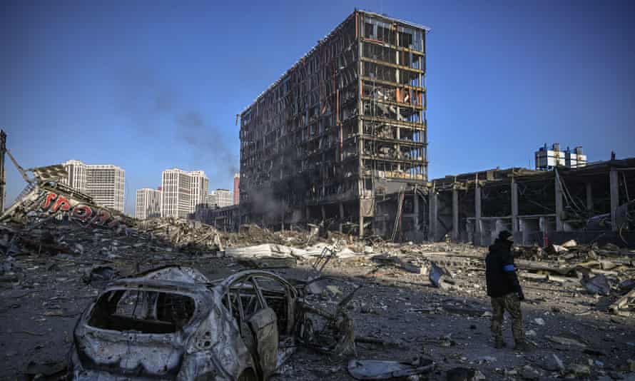 Ein ukrainischer Soldat geht vor dem zerstörten Einkaufszentrum Retroville zwischen Trümmern hindurch