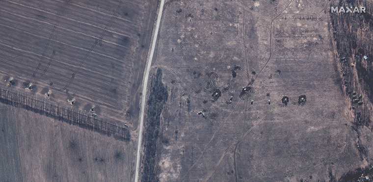 Russische selbstfahrende Artillerie auf einem Feld, deren Türme auf das Zentrum von Izyum zeigen.