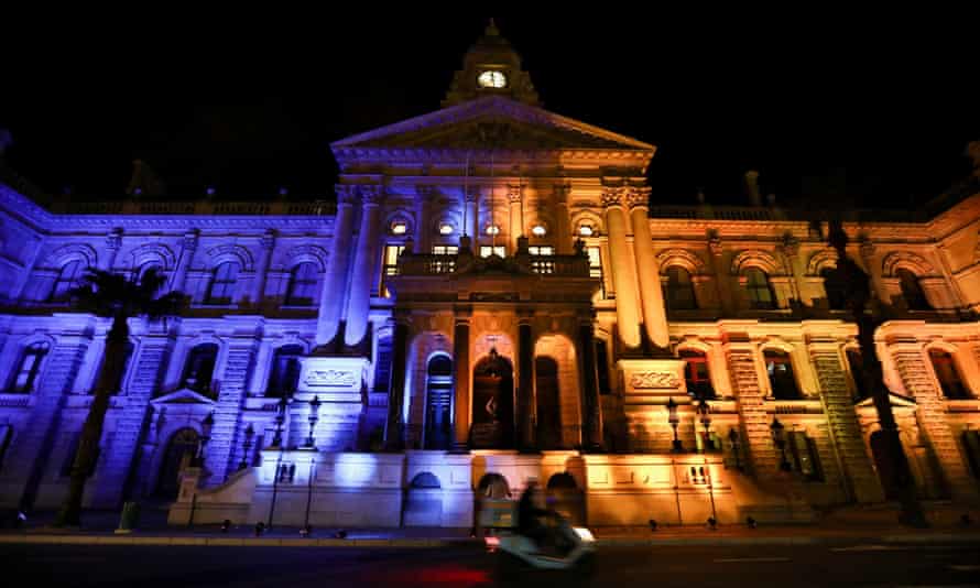 Ein Motorradfahrer passiert am 2. März das in den Farben der ukrainischen Flagge beleuchtete Rathaus von Kapstadt.