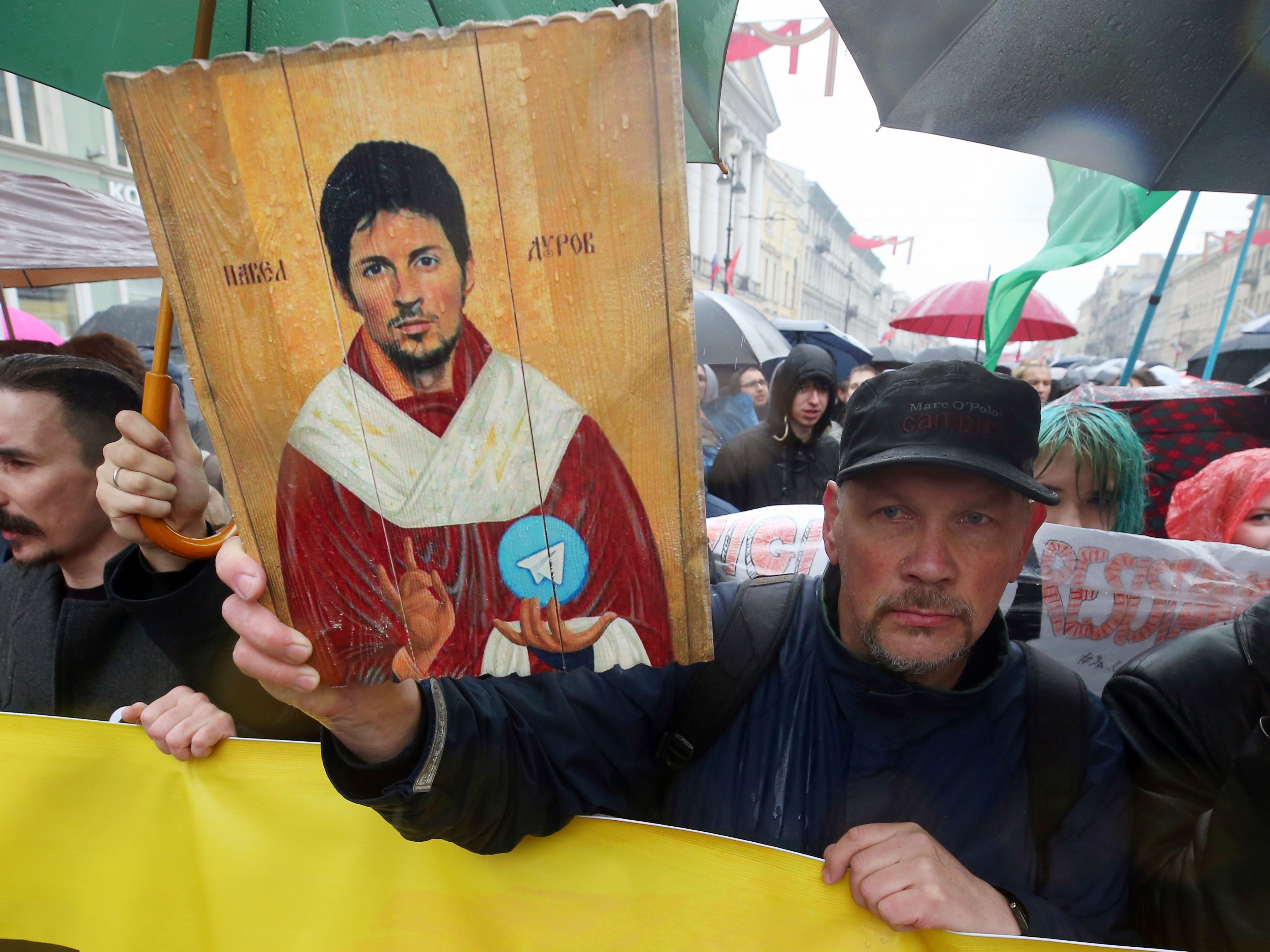 Demonstranten halten ein Zeichen von Pavel Durov, das in der Art eines katholischen Heiligen gemalt ist