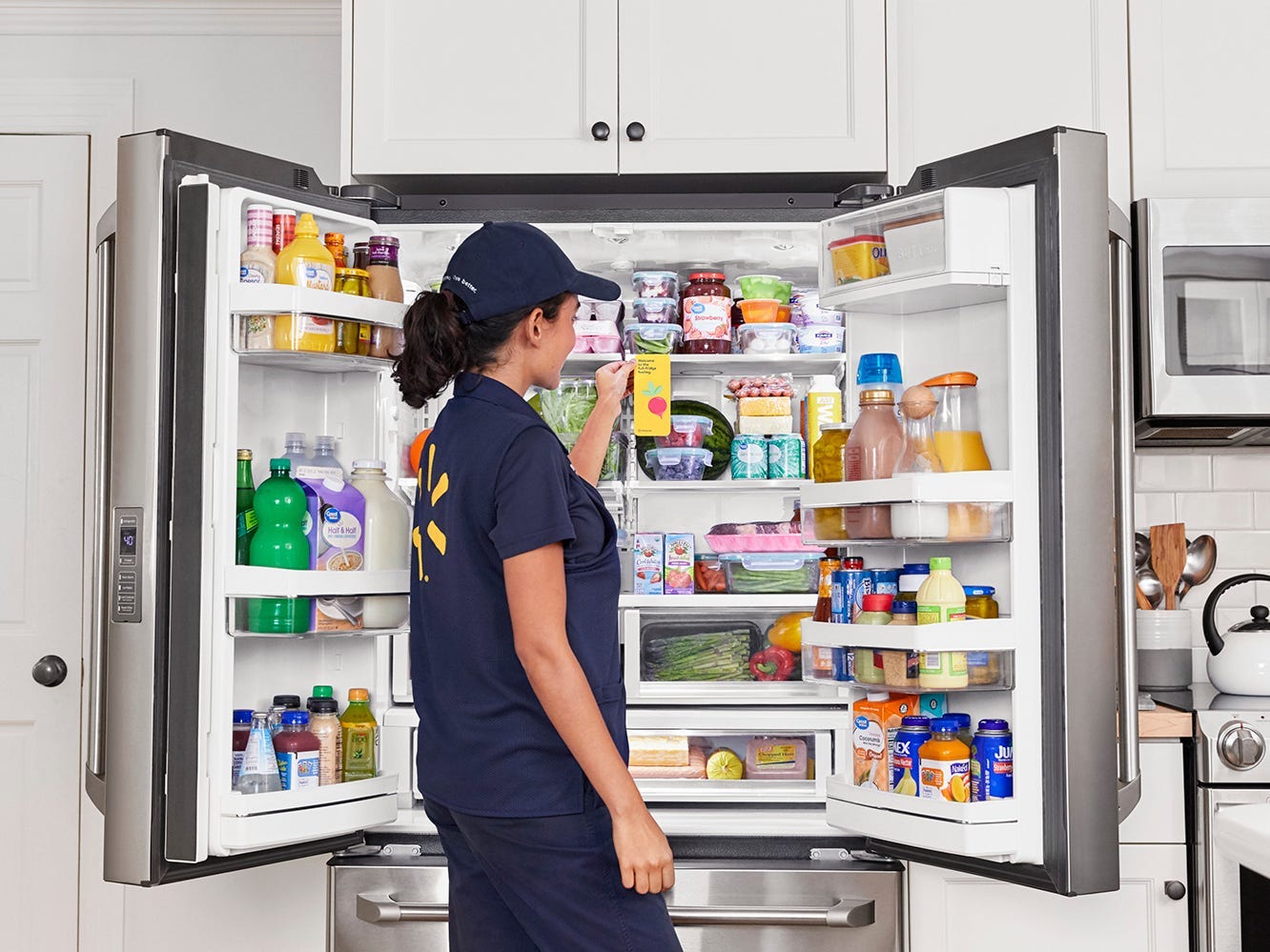 Ein Walmart-Mitarbeiter räumt im Rahmen des Walmart InHome-Lieferservices Lebensmittel in einen Kühlschrank.