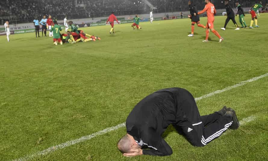 Algeriens Trainer Djamel Belmadi reagiert auf die Niederlage, während Kameruns Spieler im Hintergrund feiern.