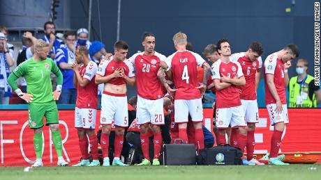 Dänemarks Spieler sehen niedergeschlagen aus, als Teamkollege Christian Eriksen (versteckt) während des EM-Spiels 2020 gegen Finnland medizinisch behandelt wird.