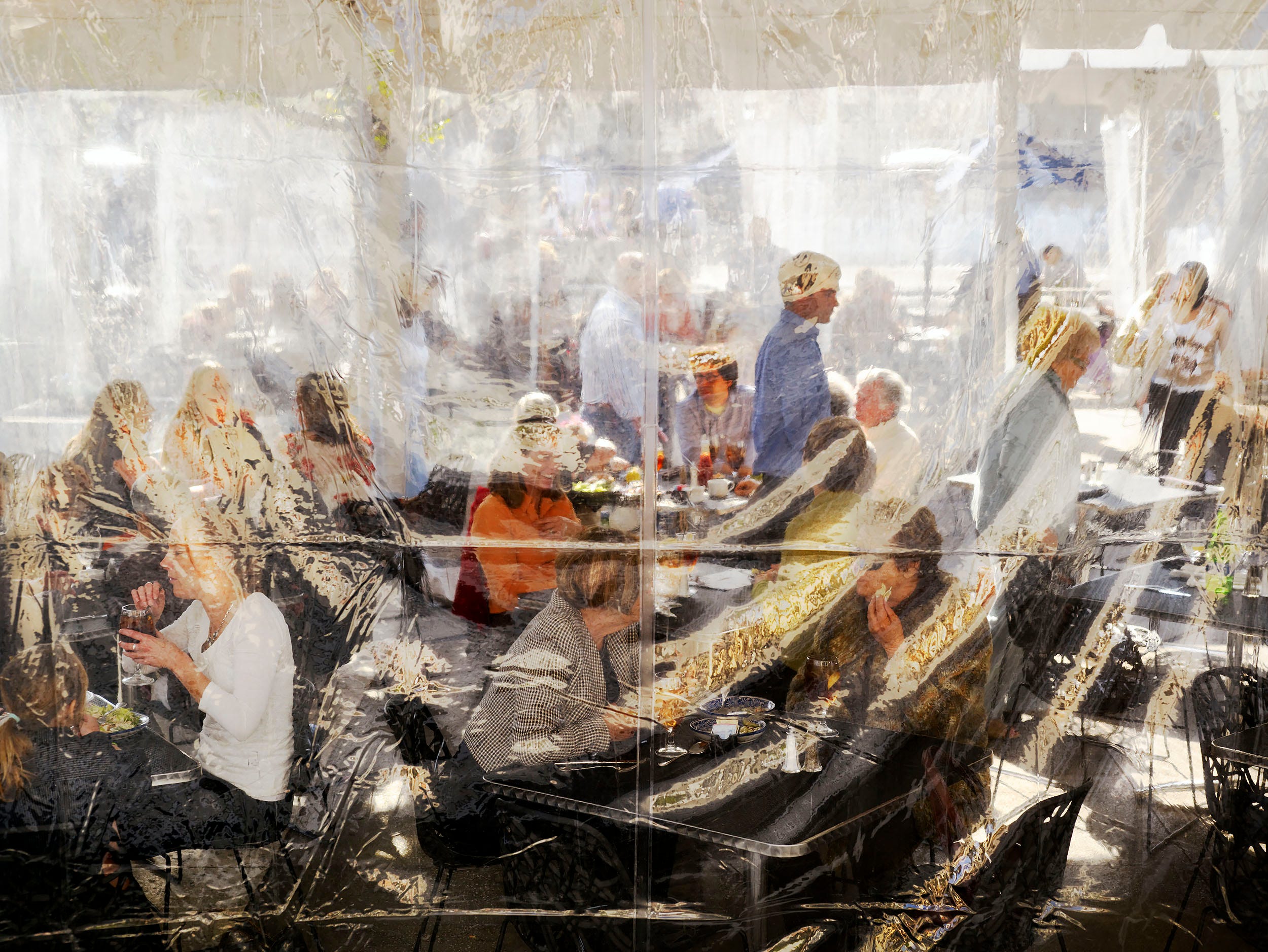 Eine Menschenmenge in einem gut besuchten Restaurant speist hinter einem durchsichtigen Plastikvorhang.