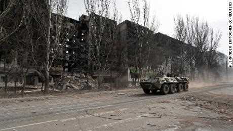 Ein gepanzertes Fahrzeug mit prorussischen Truppen fährt am 31.03.2022 entlang einer Straße an einem zerstörten Wohnhaus in der belagerten südlichen Hafenstadt Mariupol vorbei.