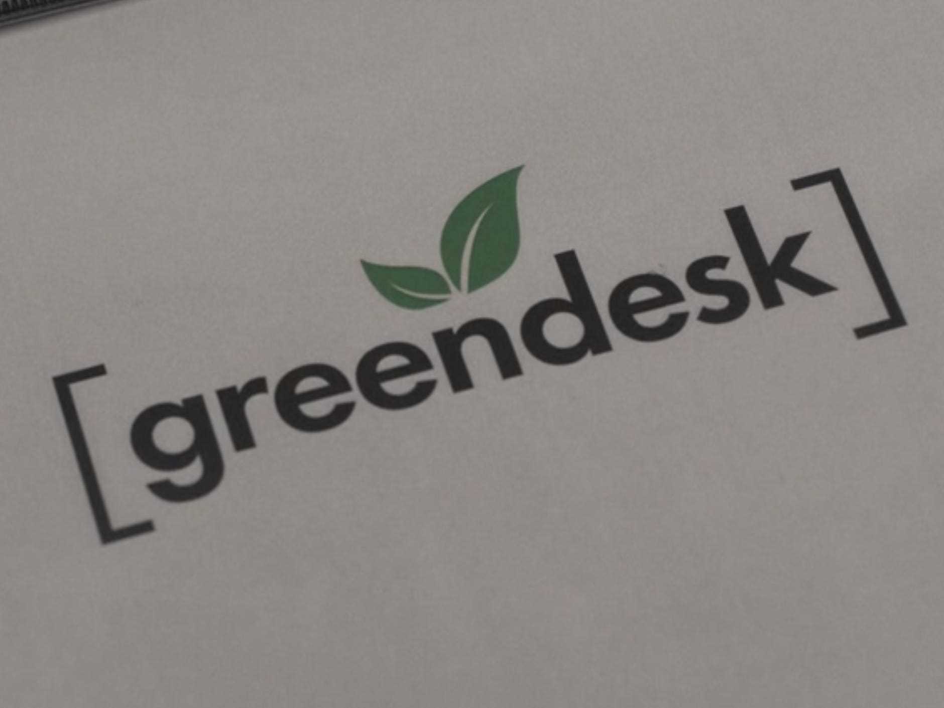 ein Blatt Papier, auf dem Greendesk steht, mit einem kleinen Blattmuster über dem n und Klammern darum herum