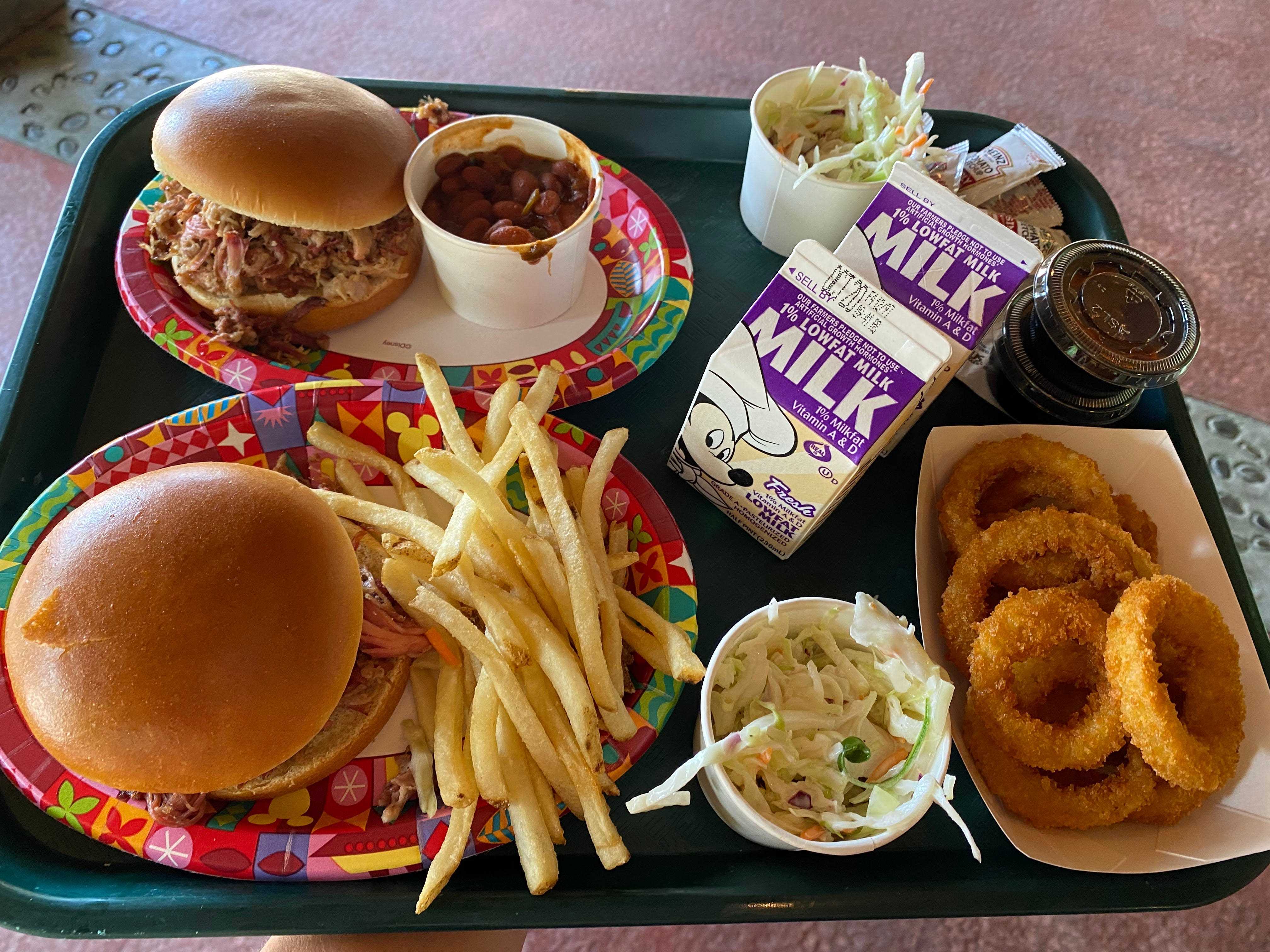 Cafeteria-Tablett mit Pulled Pork-Sandwiches, Zwiebelringen und Getränken aus dem Disney-Tierreich