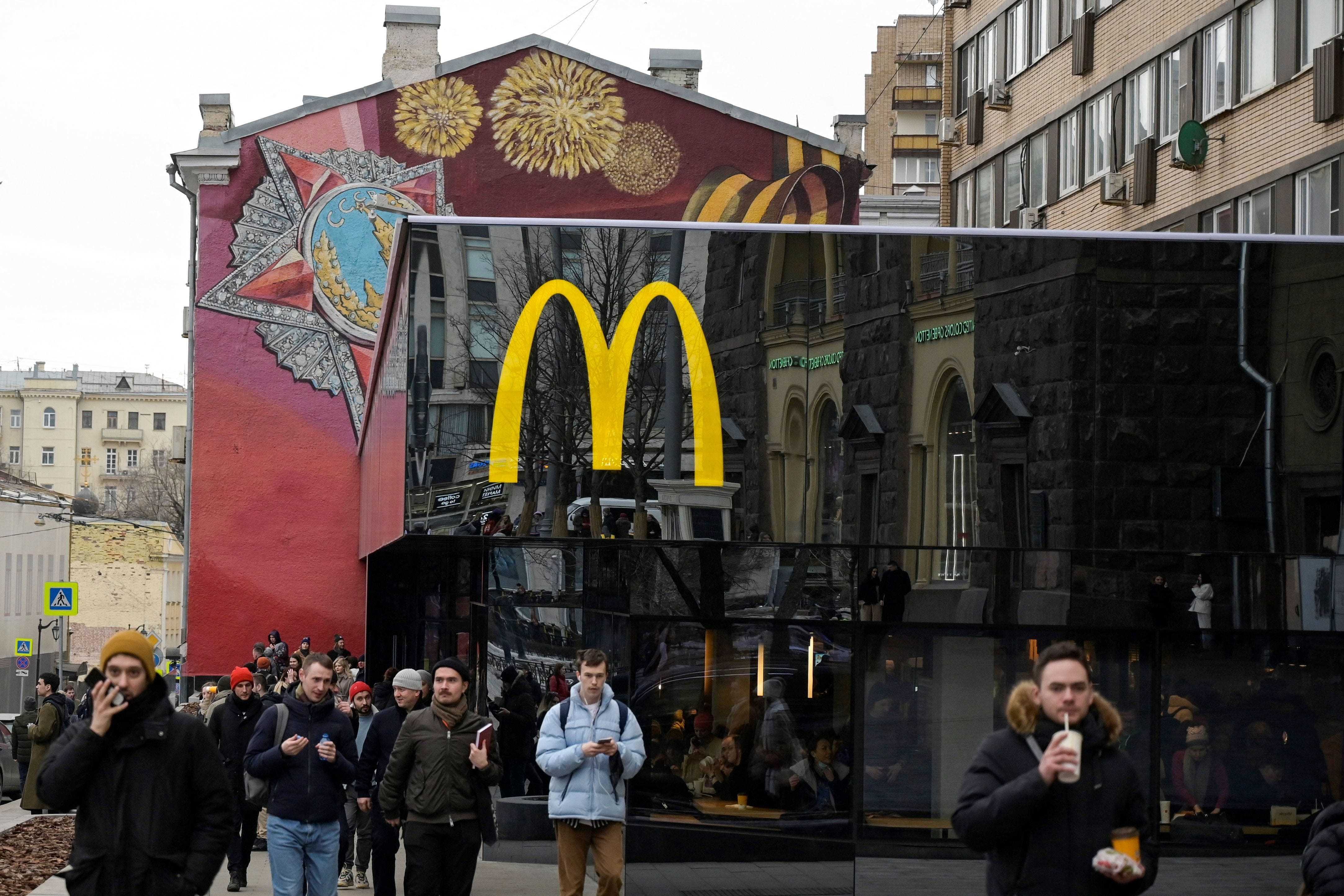 Männer gehen am 13. März 2022, dem letzten Tag von McDonald's in Russland, vor dem Flaggschiff-Restaurant von McDonald's am Puschkinskaja-Platz im Zentrum von Moskau.