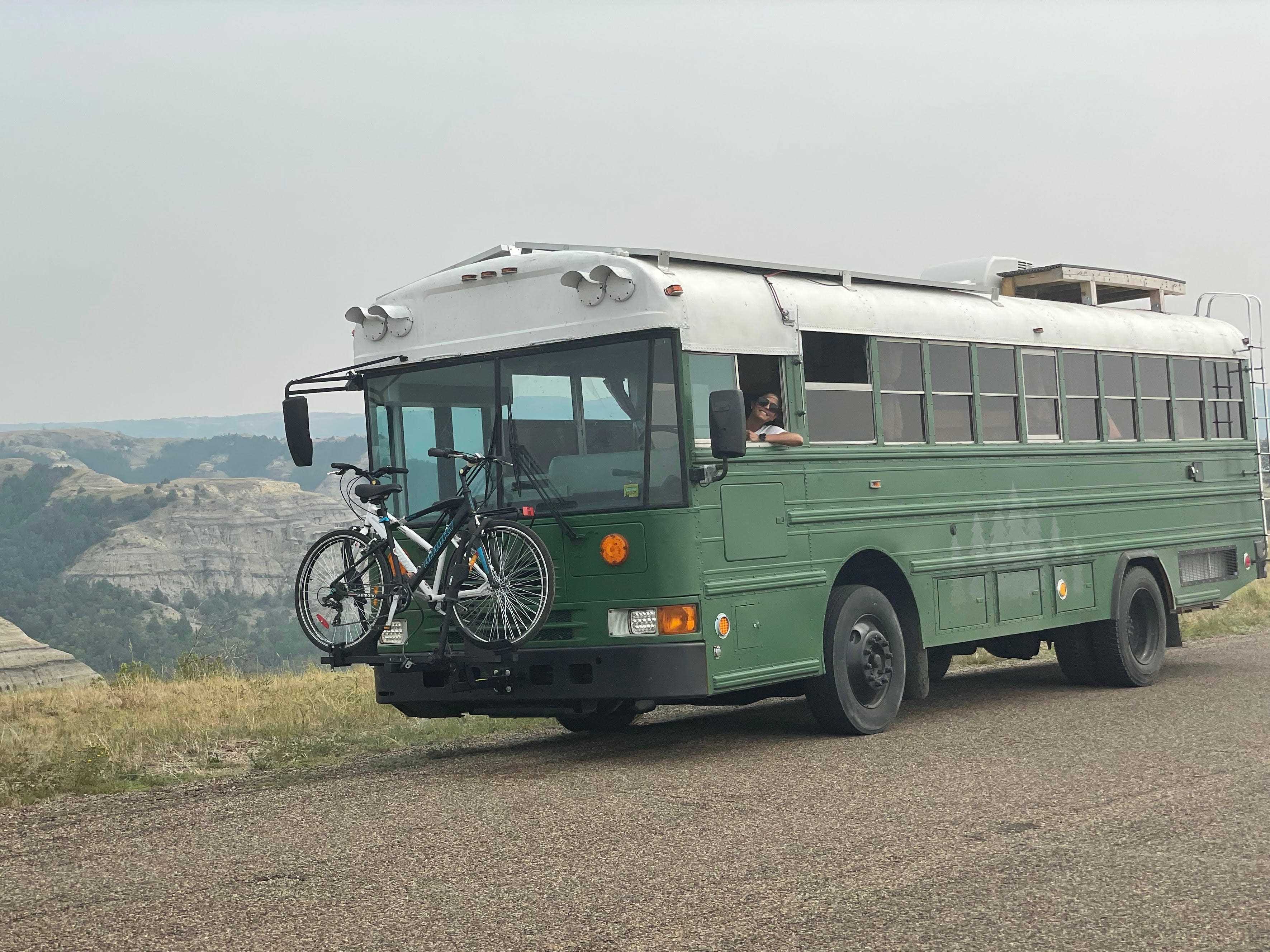 Ein grüner Bus auf einer Schotterstraße mit Bergkette im Hintergrund