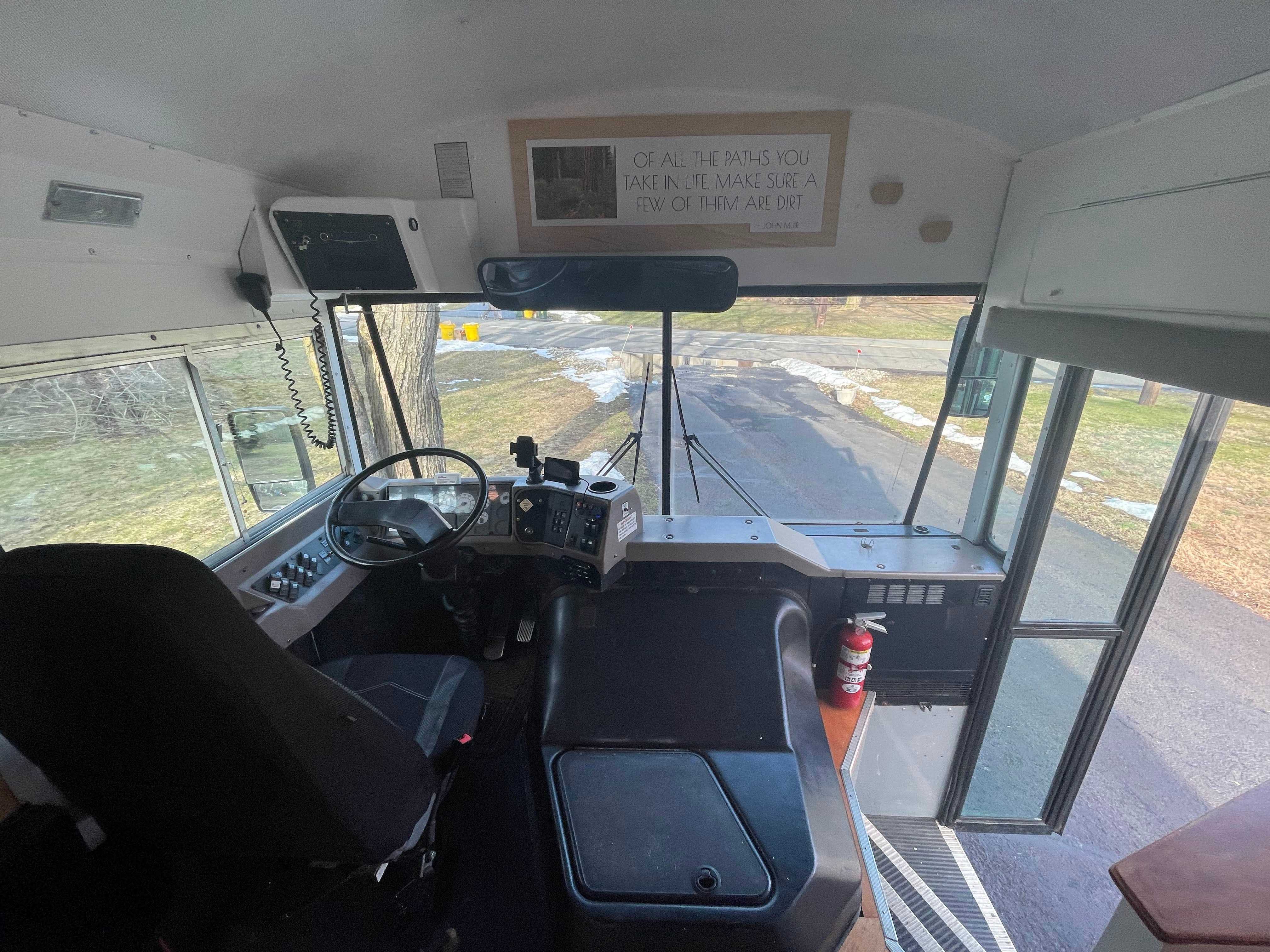 Vorderer Bereich des Busses mit offenen Türen, schwarzem Fahrersitz und schwarzem Lenkrad